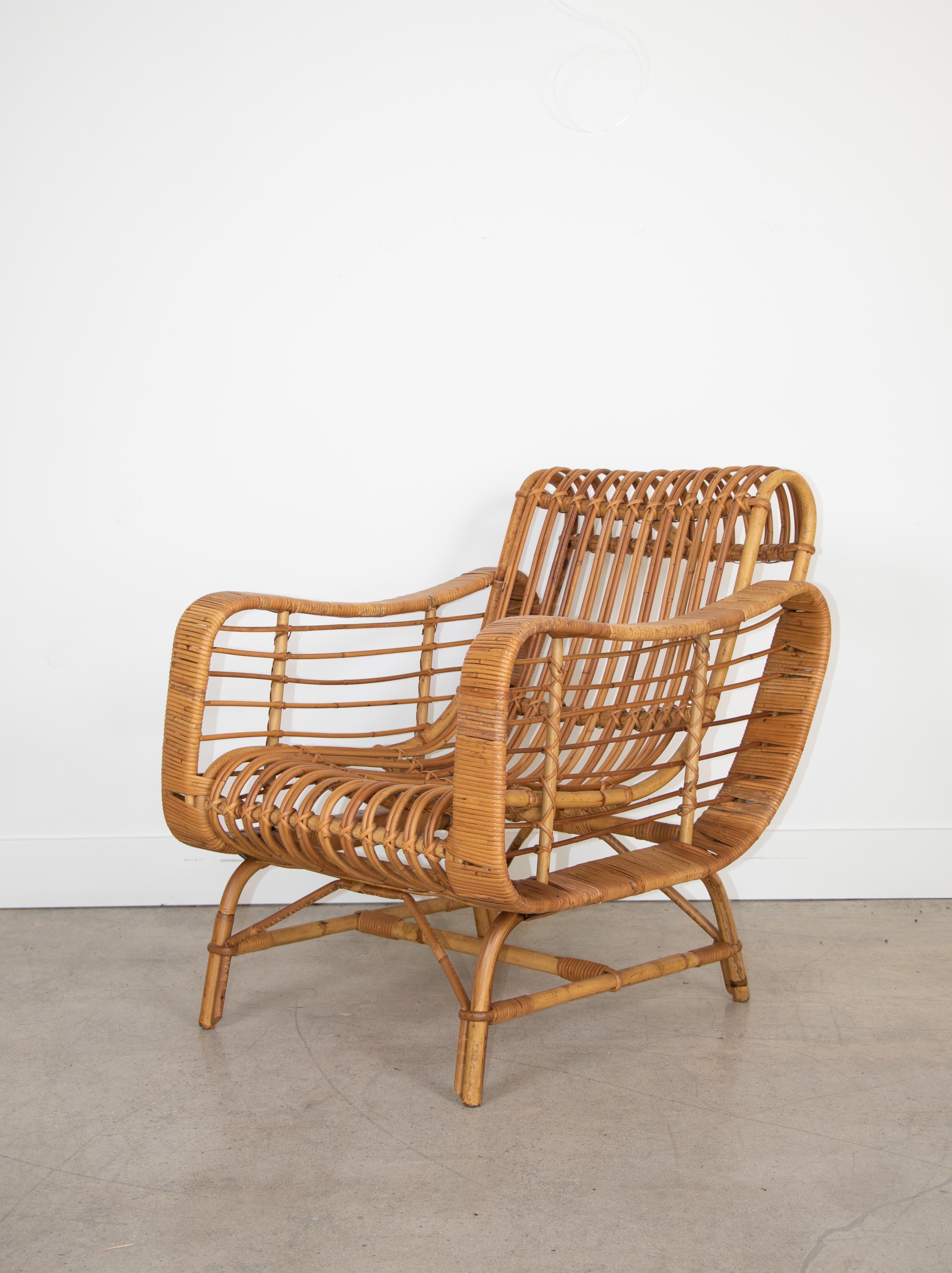 Italian rattan lounge chair with sculptural form and unique detail. Reclined curved back and fully wrapped armrests. Stunning piece.