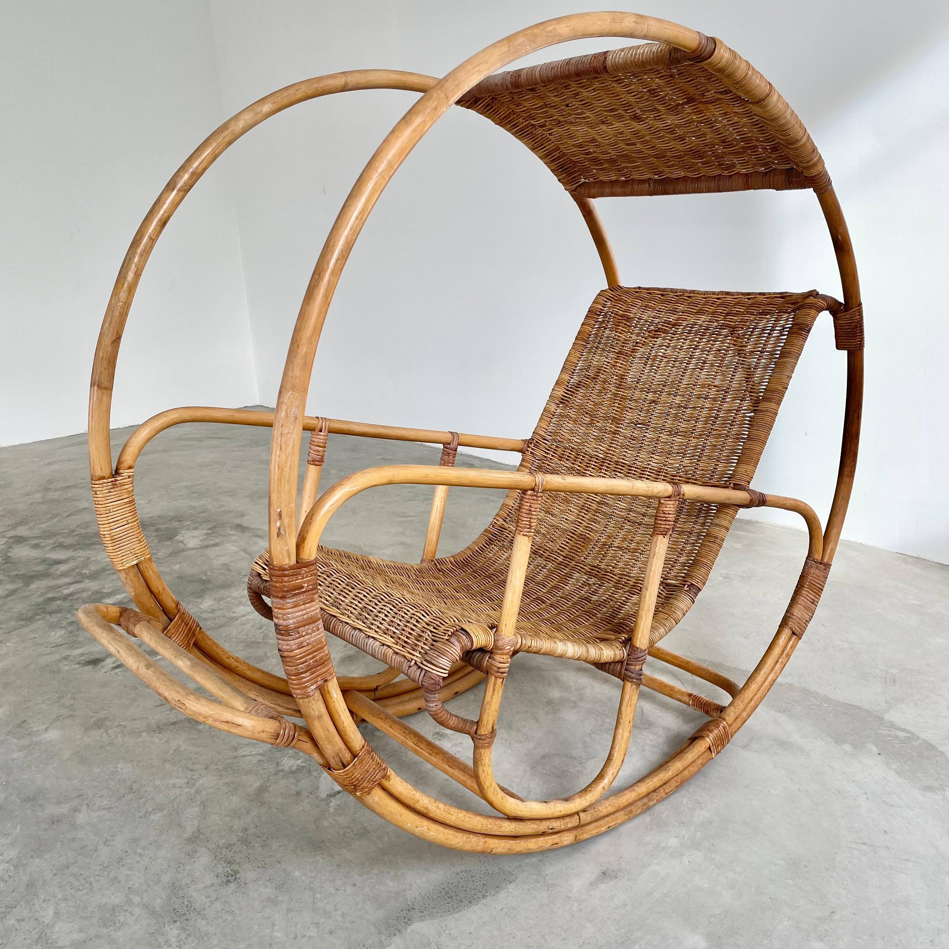 Stunning rattan rocking chair inspired by Franco Bettonica and the space age of the 1960s. He sought to create a chair using traditional natural materials but bending and weaving them into futuristic shapes. This chair features a bamboo wheel frame