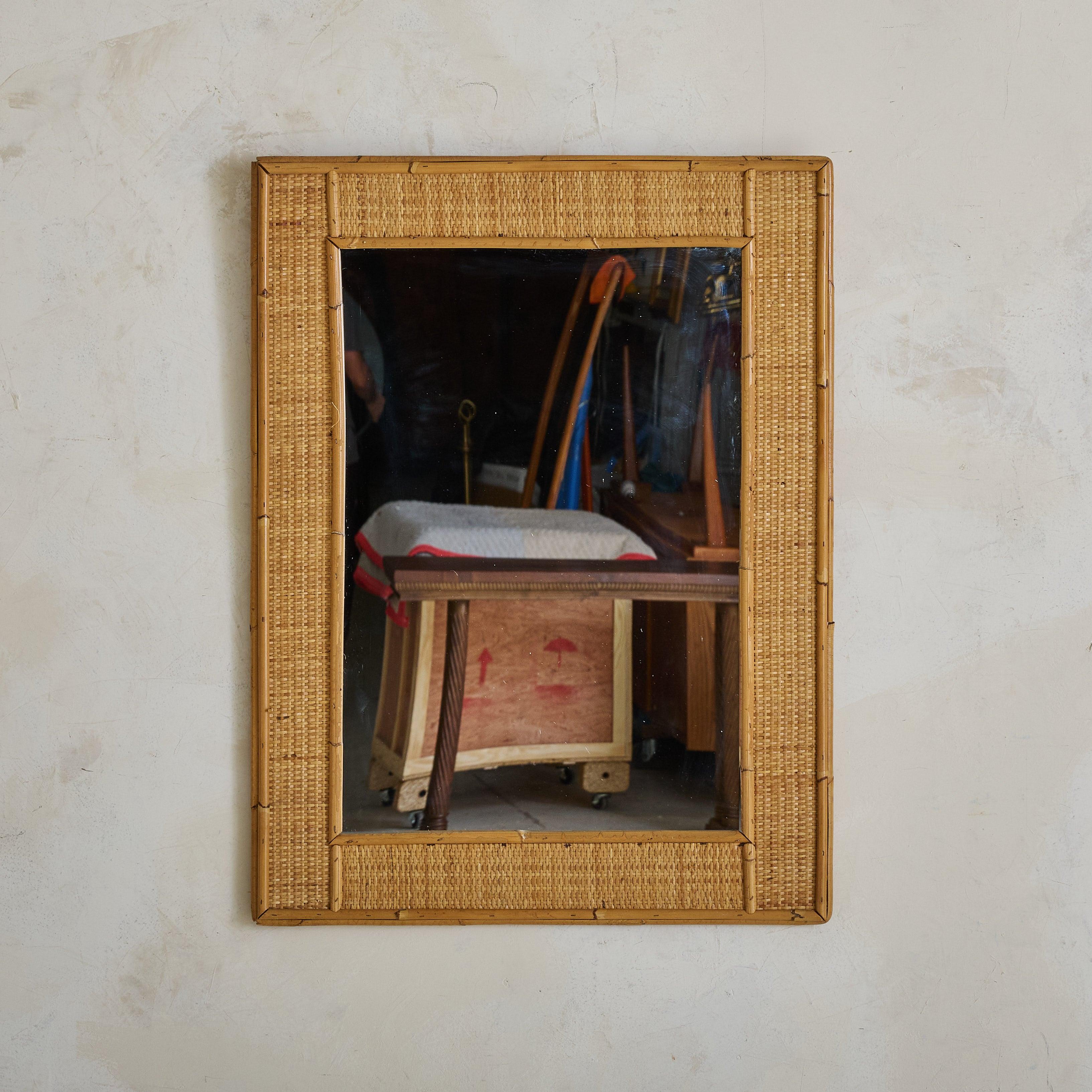Espejo de pared italiano de los años 60, fabricado con ratán natural y bambú. Su silueta rectangular está meticulosamente tejida y hábilmente elaborada, mostrando la belleza de los materiales naturales. Este espejo tiene el fondo de madera e incluye