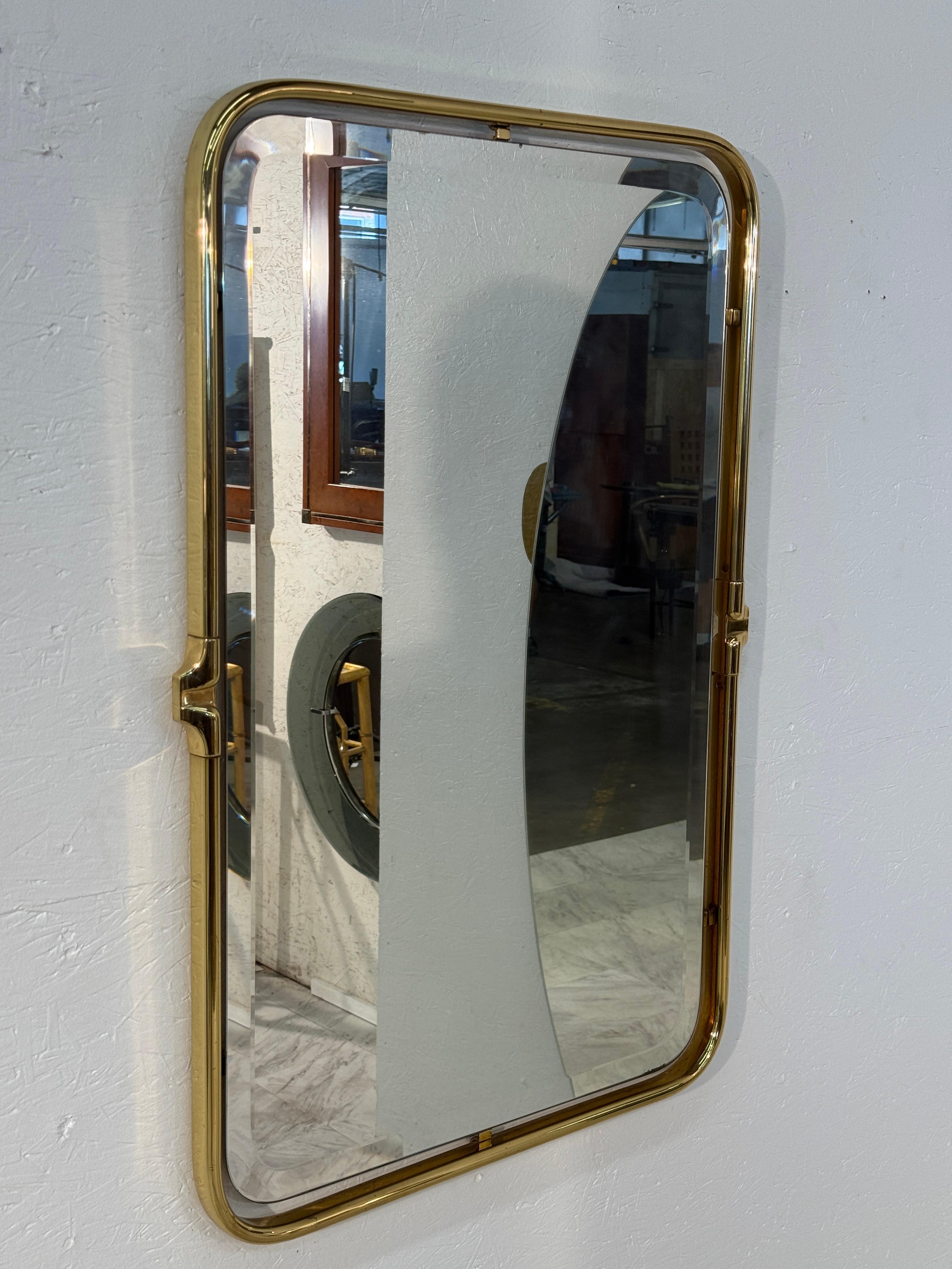 A sophisticated Italian wall mirror in a rectangular form with gently rounded corners, framed in polished brass. Subtle design details, including elegant side mounts, enhance its mid-century character while maintaining a clean and timeless