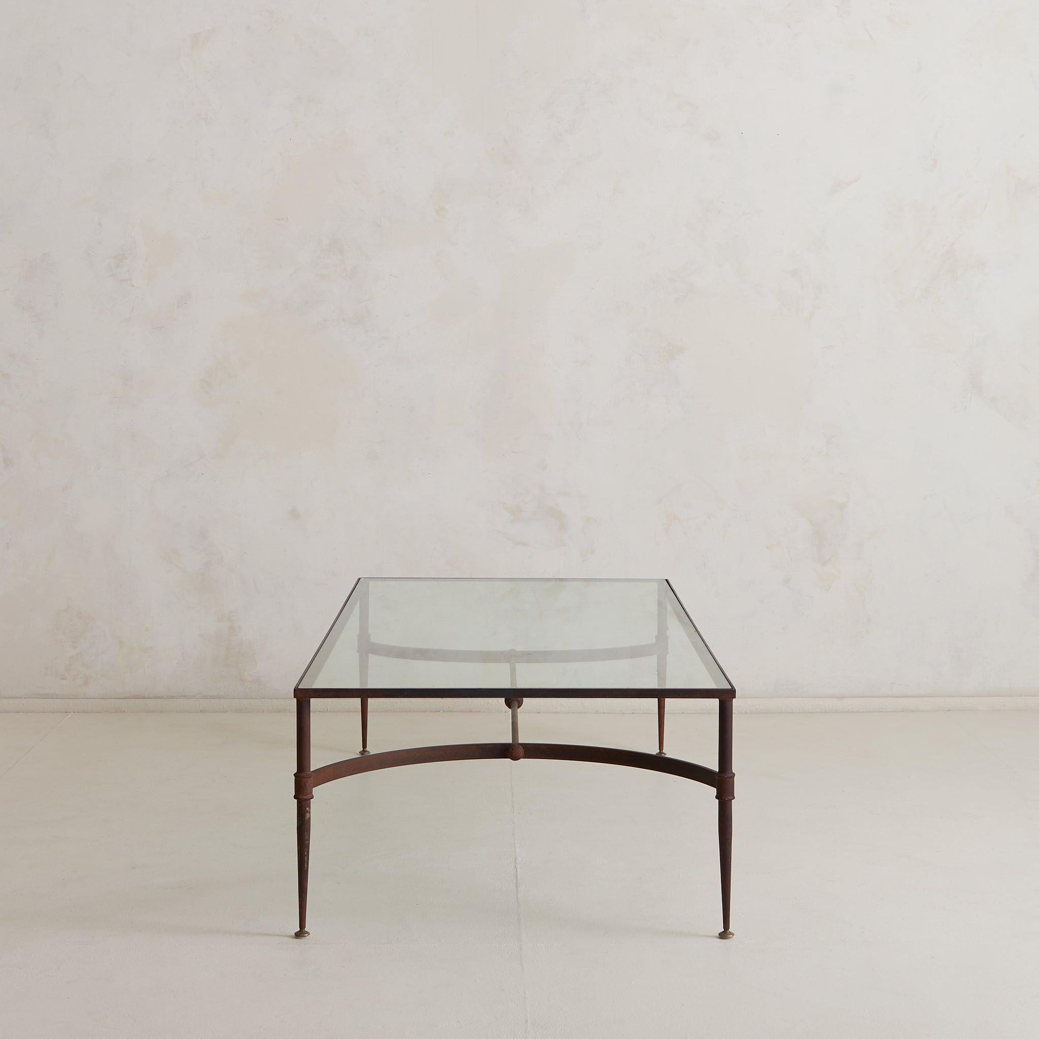 This generous Italian coffee table from the 1960s embodies a quiet monumentality. Its elongated frame, composed of hand-forged iron, balances architectural precision with artisanal softness—each tapered leg terminating in a fine brass foot, the