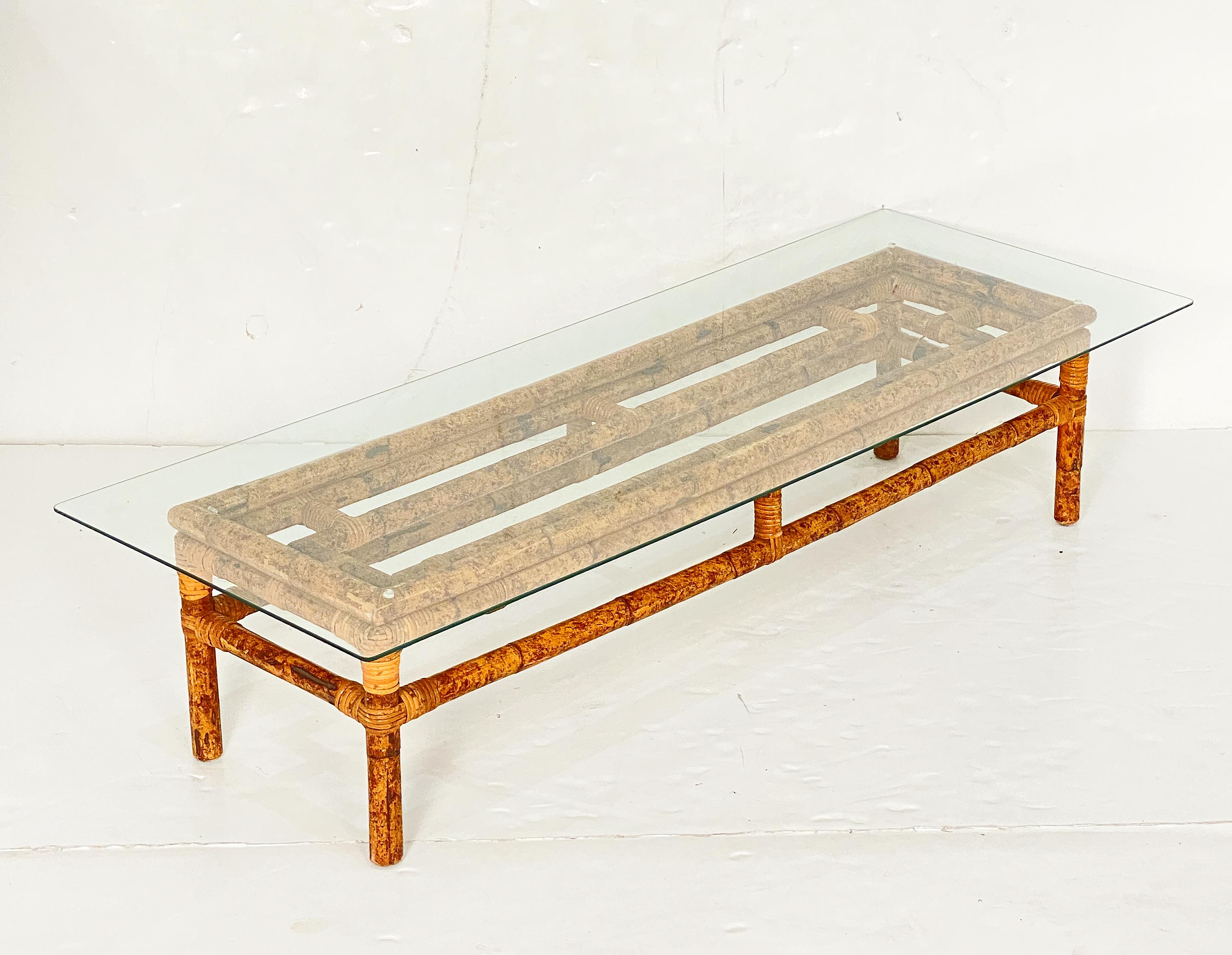 A fine Italian Mid-Century Modern low or coffee or cocktail table - featuring a removable rectangular glass top set upon a frame of woven wicker rattan and bamboo with four legs.  
