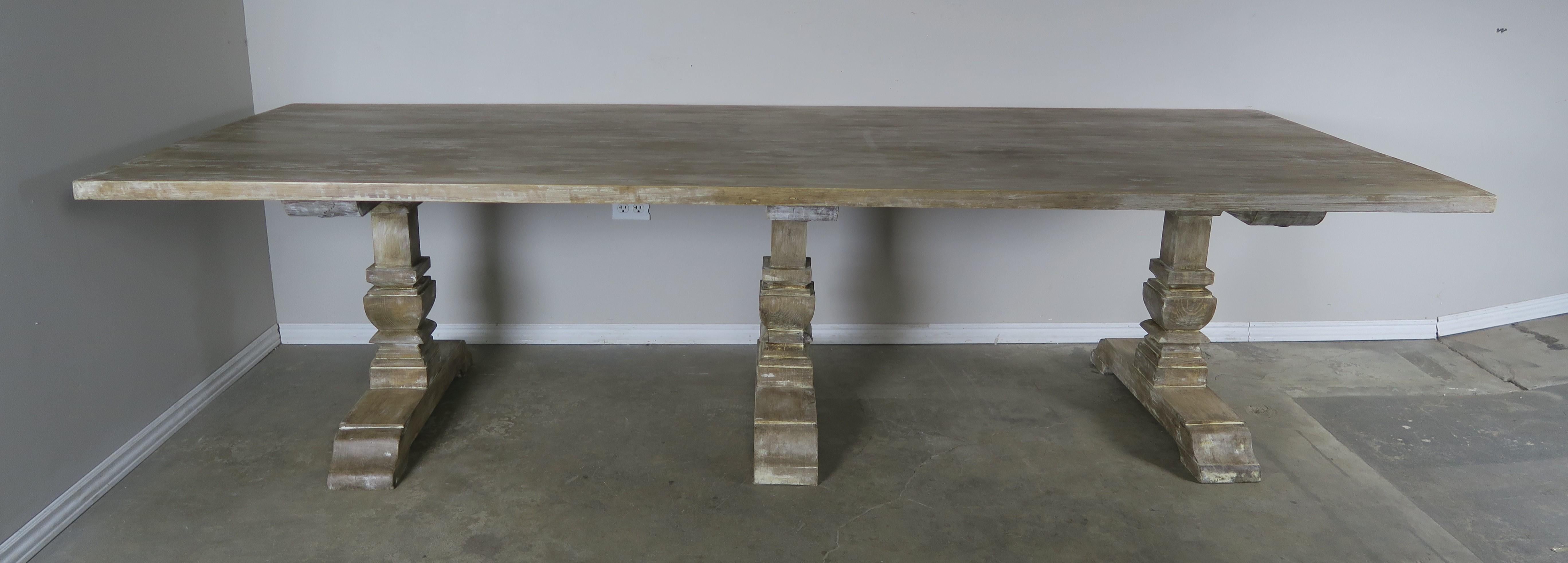 Italian white washed 3-pedestal dining table. A large rectangular shaped top sits on three carved wood pedestals. The finish is beautifully weathered with light white wash accents.