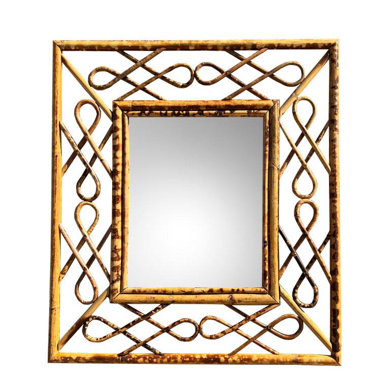 A rectangular burnt bamboo or tortoise bamboo Hollywood Regency wall mirror. This beautiful piece will add a touch of chinoiserie or traditional design to any space. The mirror is inset in a bamboo frame. The frame is created of curled scrolled