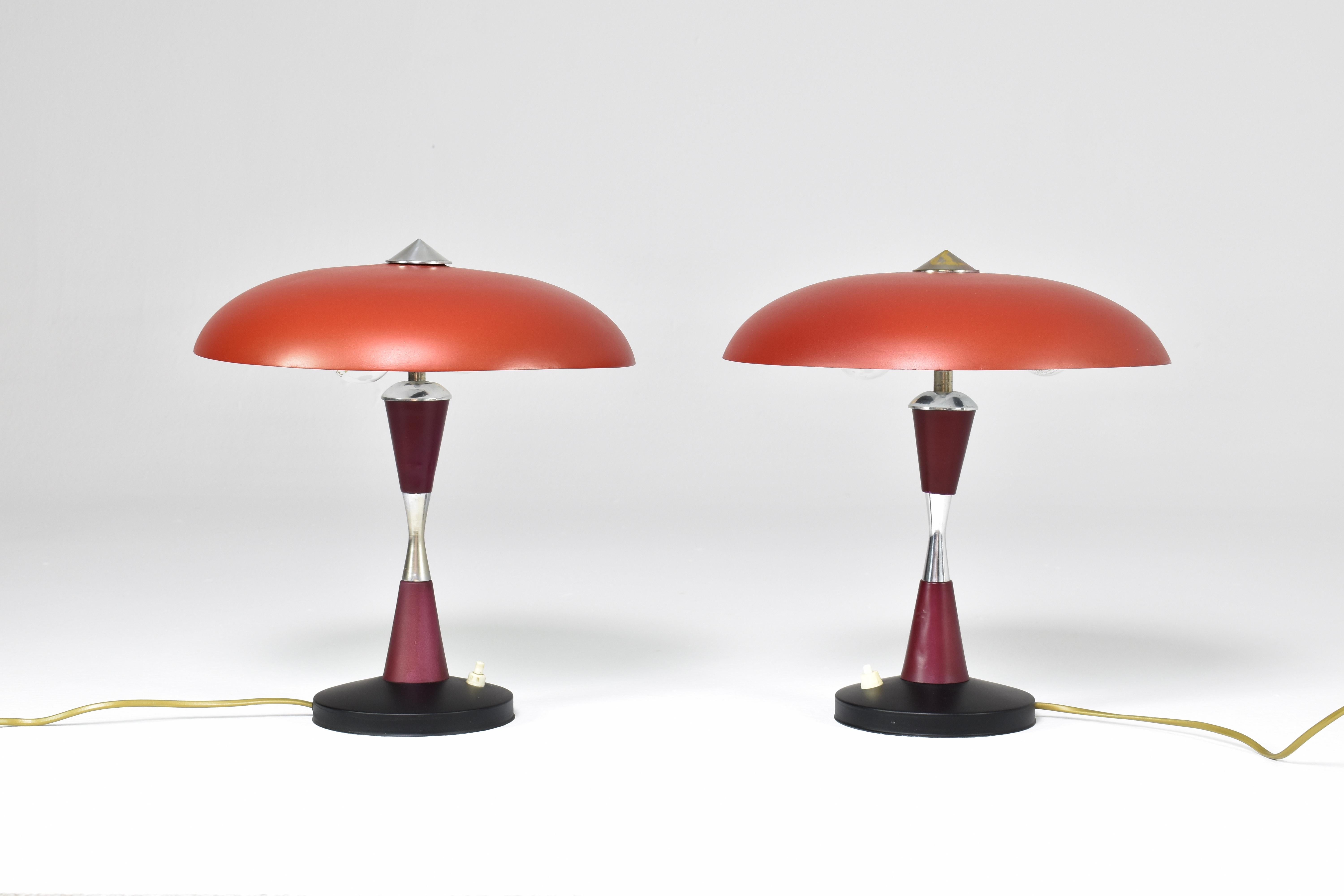 A funky pair of Italian 1960s table lamps designed with a black shade and base and a dark red stem. These accent lights are composed of aluminium and have two light bulb sockets and pretty gold brass accents. 

Professionally re-wired with the