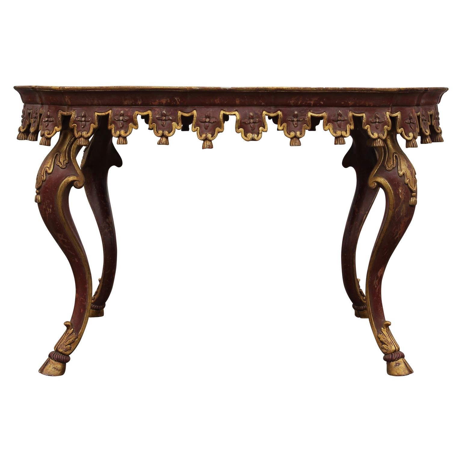 Beautiful Italian red and parcel-gilt carved tassel tea height table.
. Hoof feet
. Made in Italy
. Wonderful patina.
 