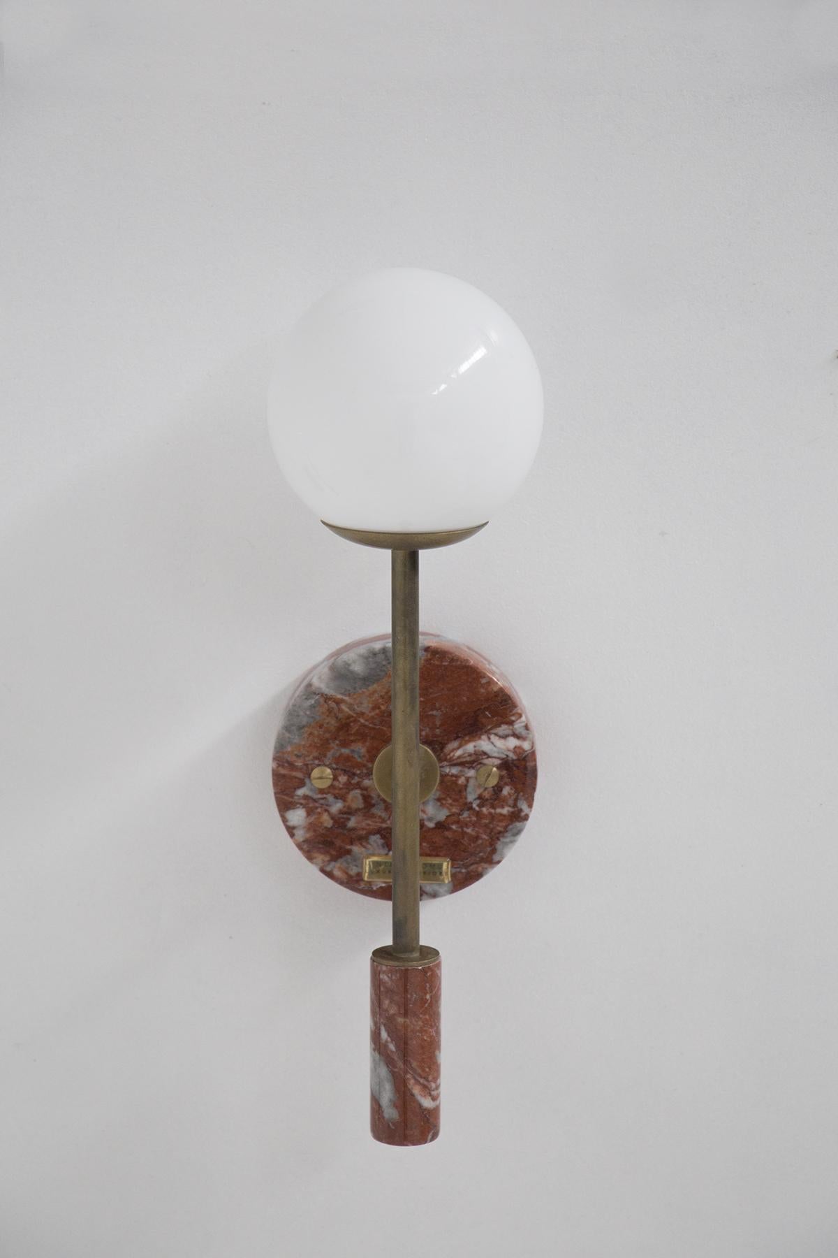 Beautiful contemporary wall lamp of Italian production after 2000. The table lamp through its sculptural forms creates a geometric game to the object. Made with a central body in red marble with a gilded brass base, the peculiarity of the lamp is