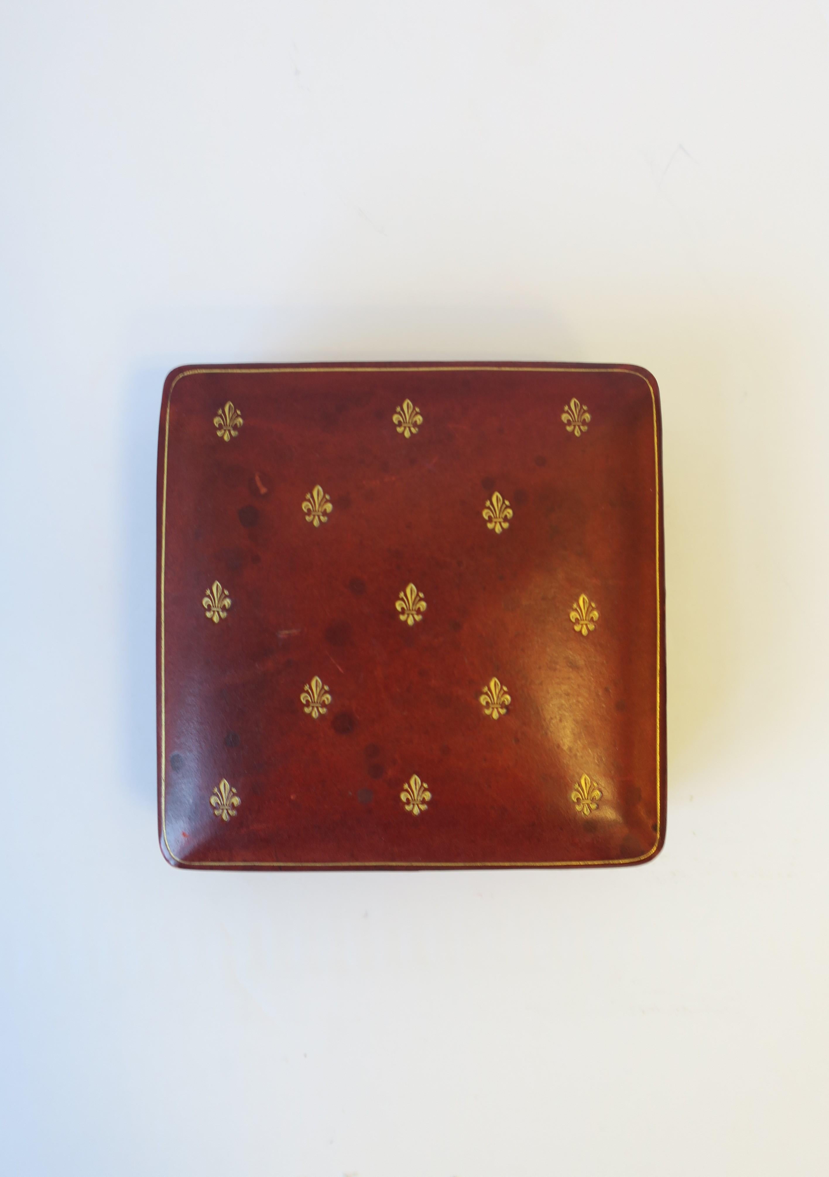 A beautiful mid-20th century Italian red, burgundy, or 'ox blood' leather jewelry, vanity or trinket box, with gold embossing and gold fleur-de-lis design on top. Marked 'LEATHER SCHOOL FLORENCE
