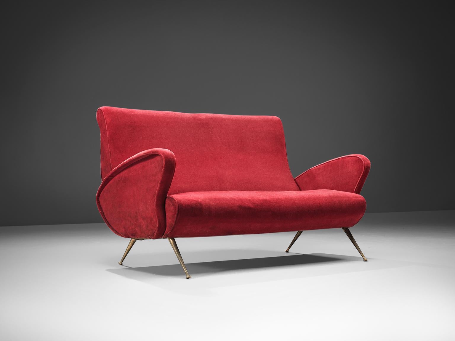 Settee, red velvet, brass, Italy, 1950s.

This sofa is an iconic example of Italian design from the 1950s. Organic and sculptural, this two-seat sofa is anything but minimalistic. Equipped with the original stiletto brass feet which are narrow