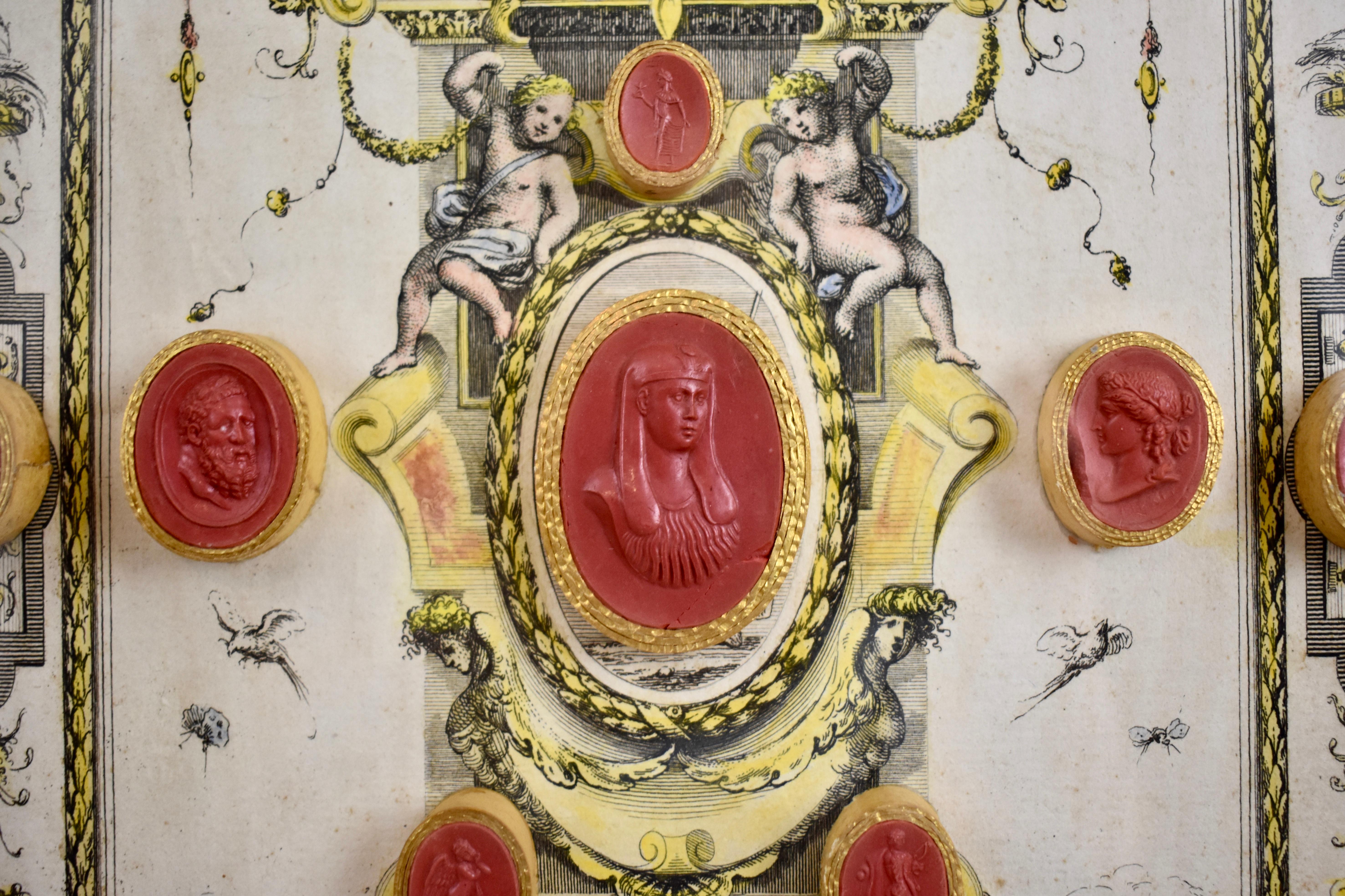 A collection of fifteen red wax Grand Tour Intaglio medallions, Italy, circa 1840. The medallions are affixed to a classical motif engraving and presented under glass in a giltwood shadowbox frame. Each seal is enclosed in a gold bezel and