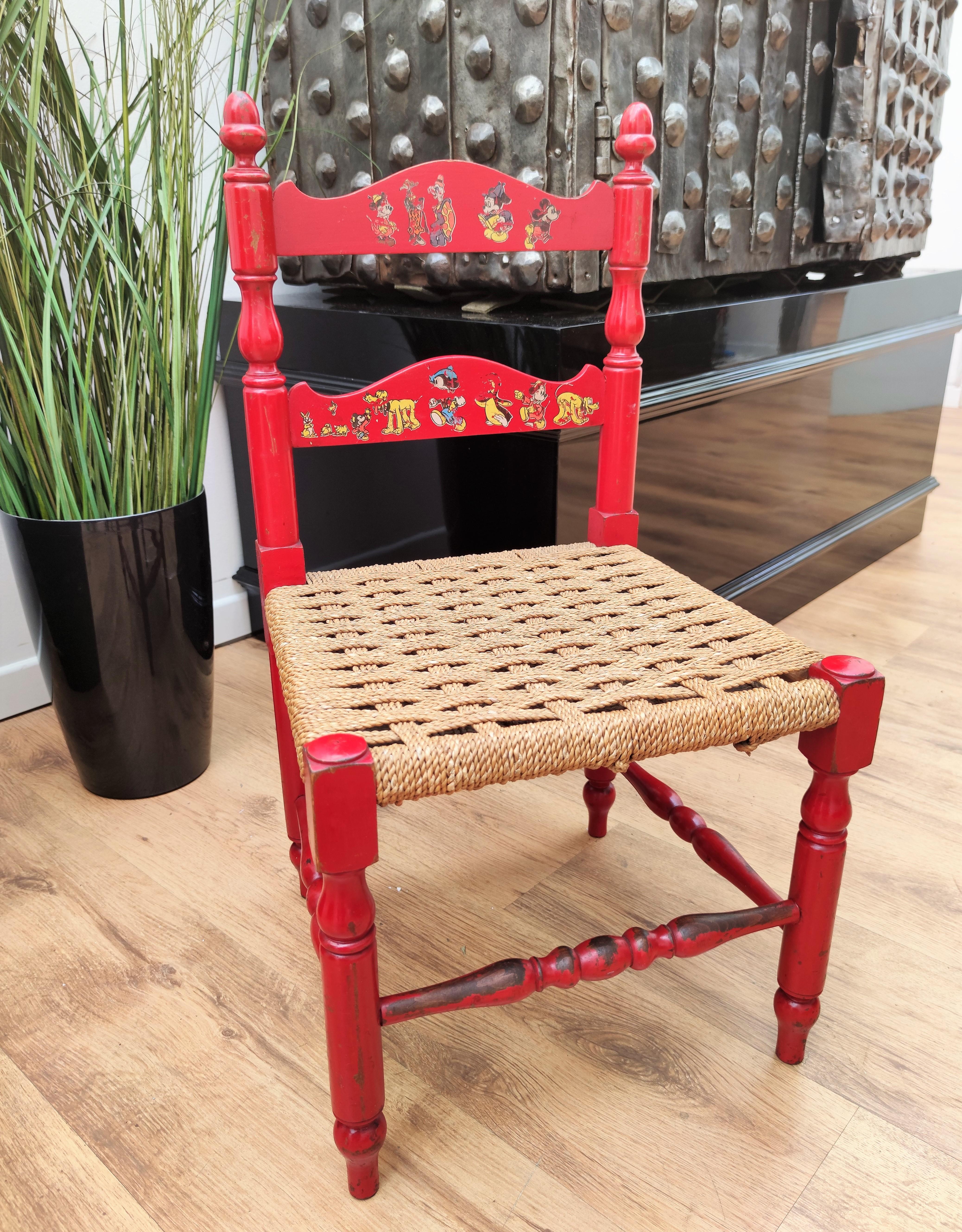 Beautiful vintage Italian kids chair in red wood structure with great patina of time and rope or rush seating with various Disney characters on the seat back.
