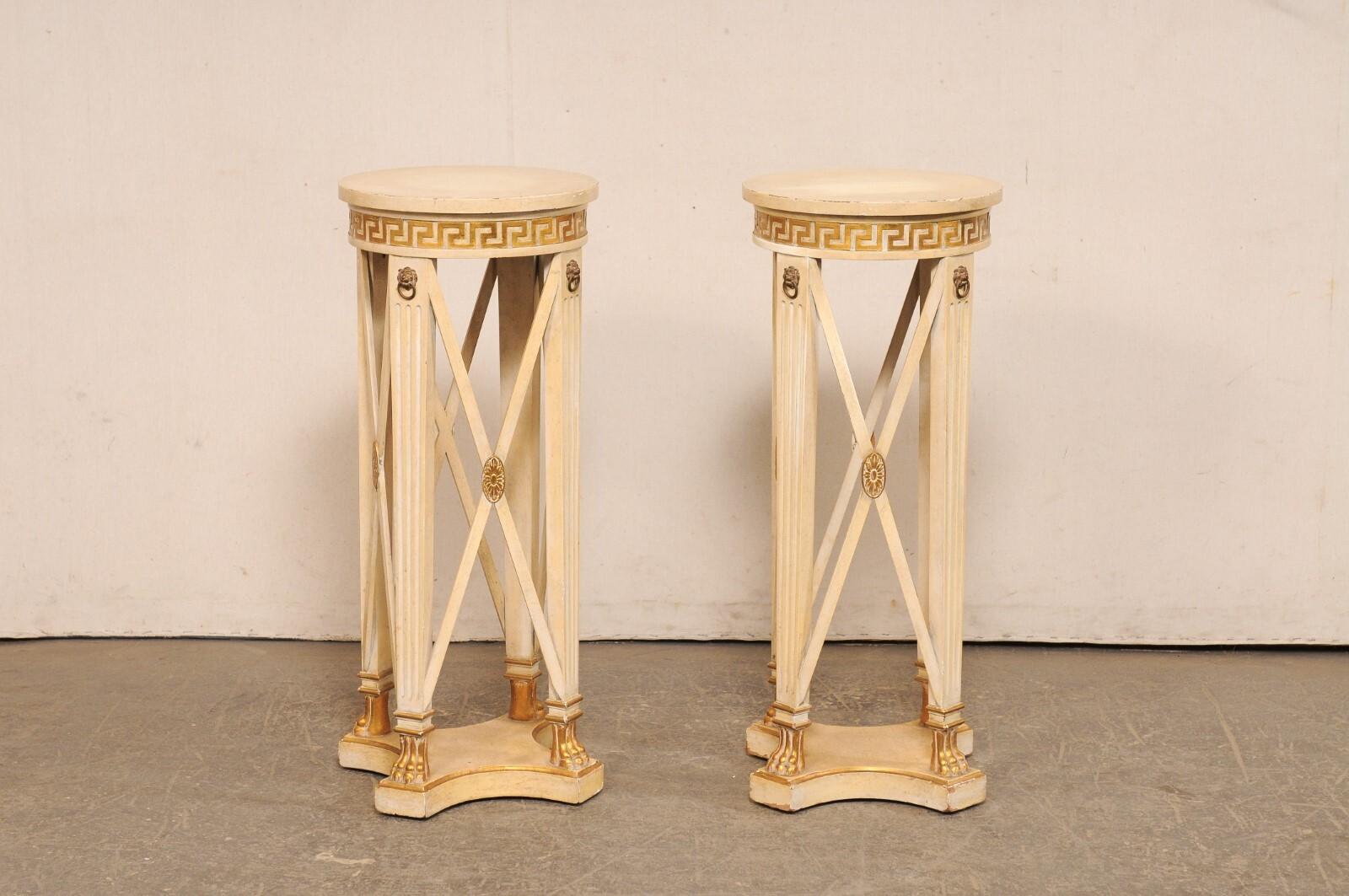 An Italian Regency style pair of carved wood pedestal tables, with Greek key accents, from the mid 20th century. This mid-century pair of tables from Italy each have a 15.25