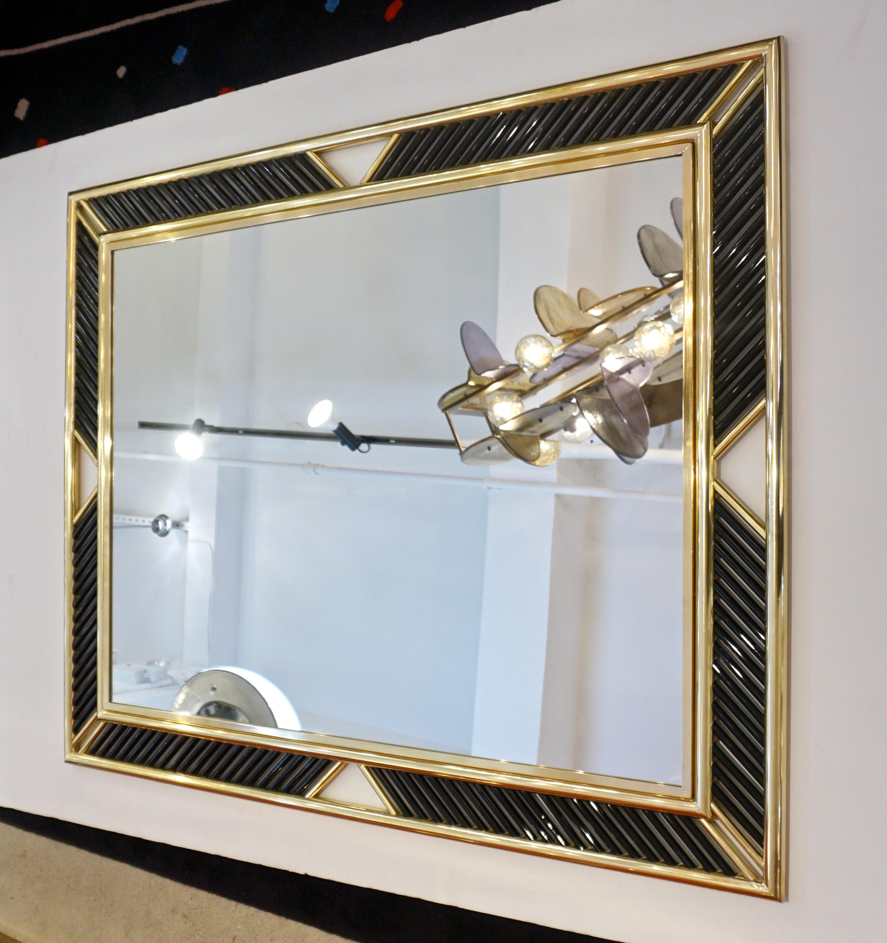 Hollywood Regency Design contemporary mirror, entirely handcrafted in Italy for Cosulich Interiors, with a modern double brass frame adorned with exquisite Murano glass rods in a solid black color that can be customized. The craftsmanship is of high