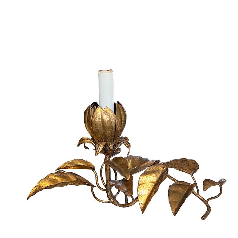 A stunning Italian Hollywood Regency Italian toleware table lamp. In gilt gold metal, this lamp is petite and takes one chandelier lightbulb. The candlestick light protrudes upward from a gilt gold lotus flower. Surrounding the flower, is a bouquet