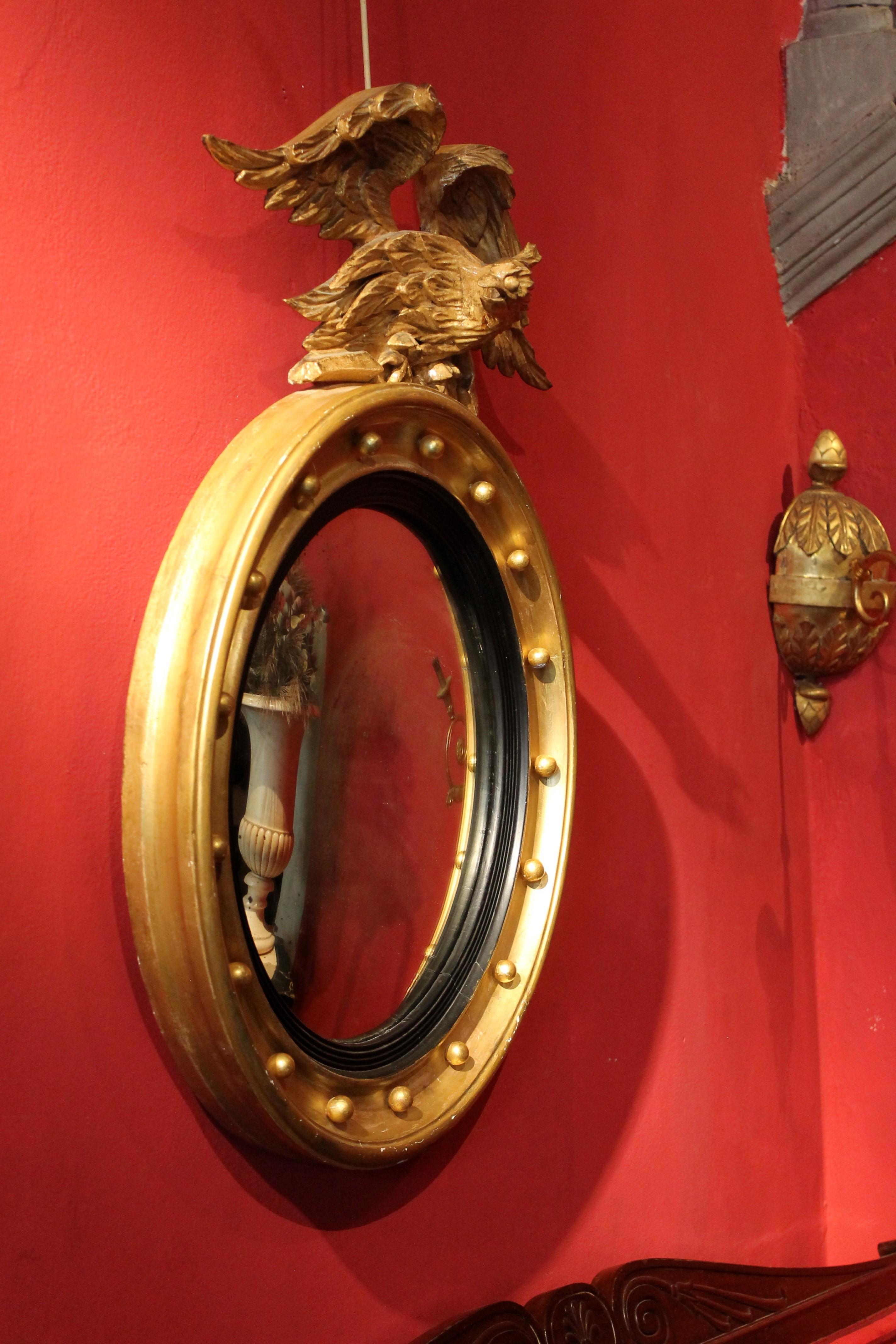 Hand-Carved Italian Regency Round Giltwood and Ebonized Convex Mirror with Carved Eagle For Sale