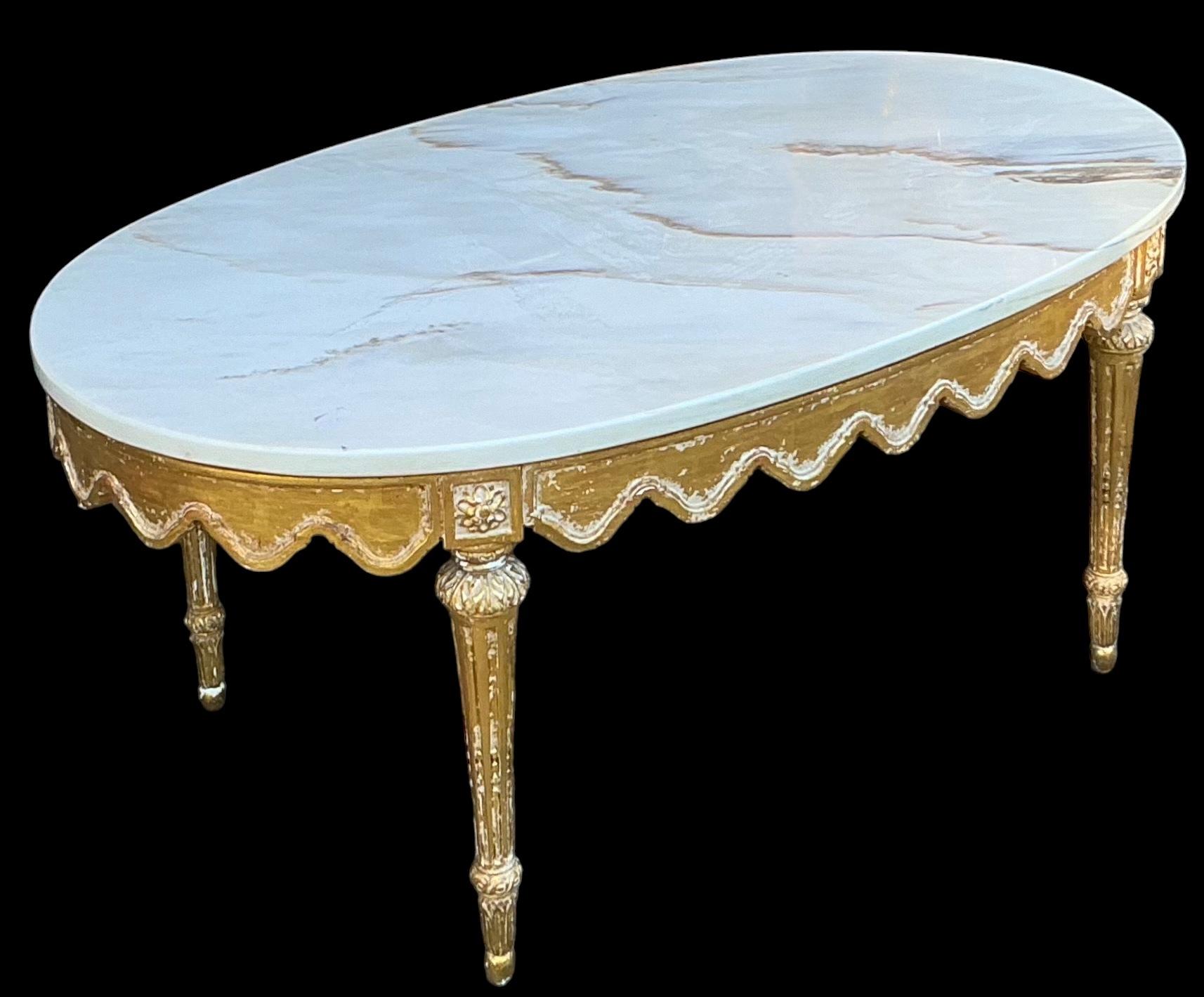  This is an Italian regency style carved giltwood and marble top coffee table. The marble is white with tan veining. It is in very good condition. The giltwood frame has some choppiness to the wood, but it does not detract from its beauty. It is