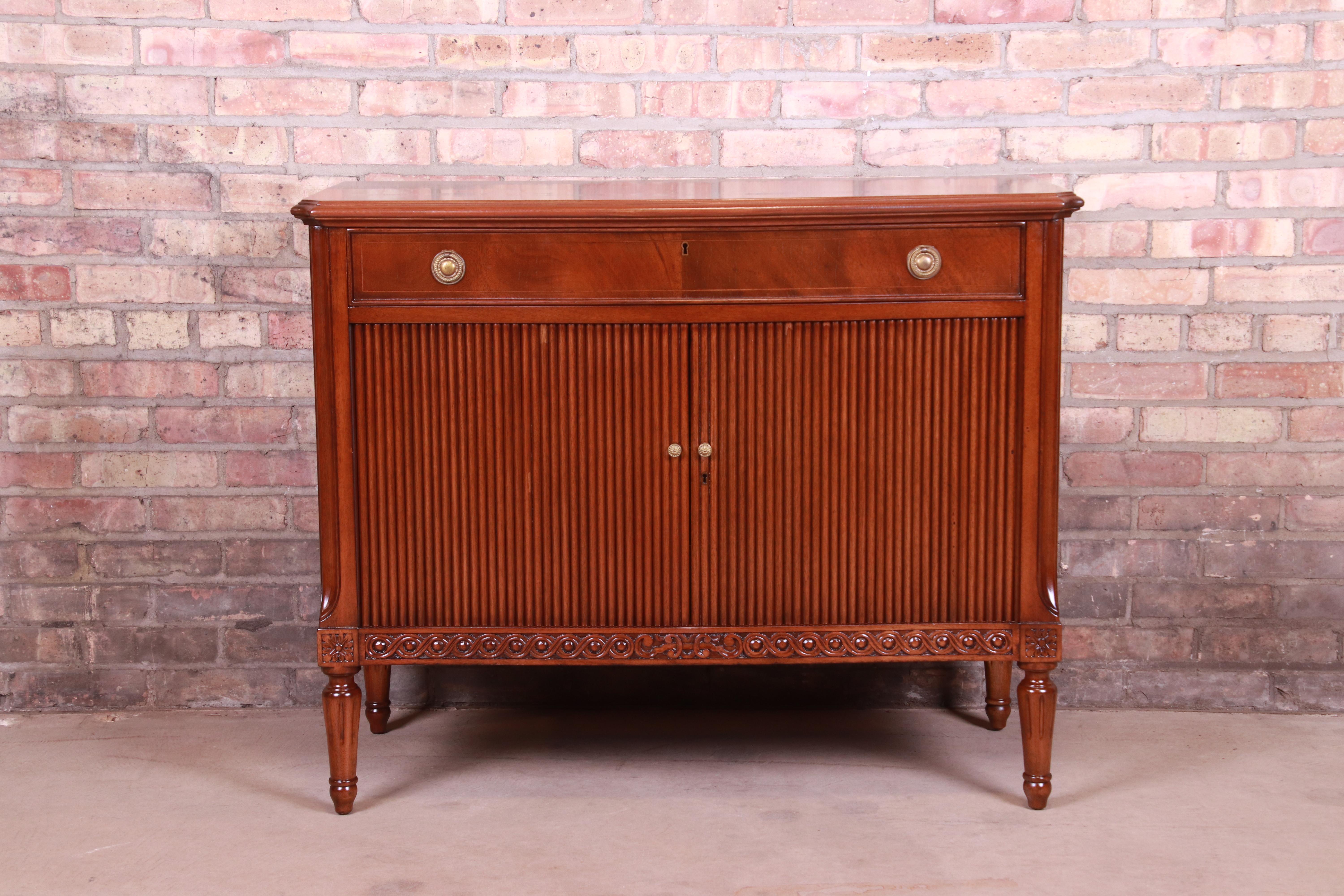 An exceptional Italian Regency style compact credenza, server, or commode,

Circa 1940s

Mahogany, with tambour door and original brass hardware.

Measures: 40