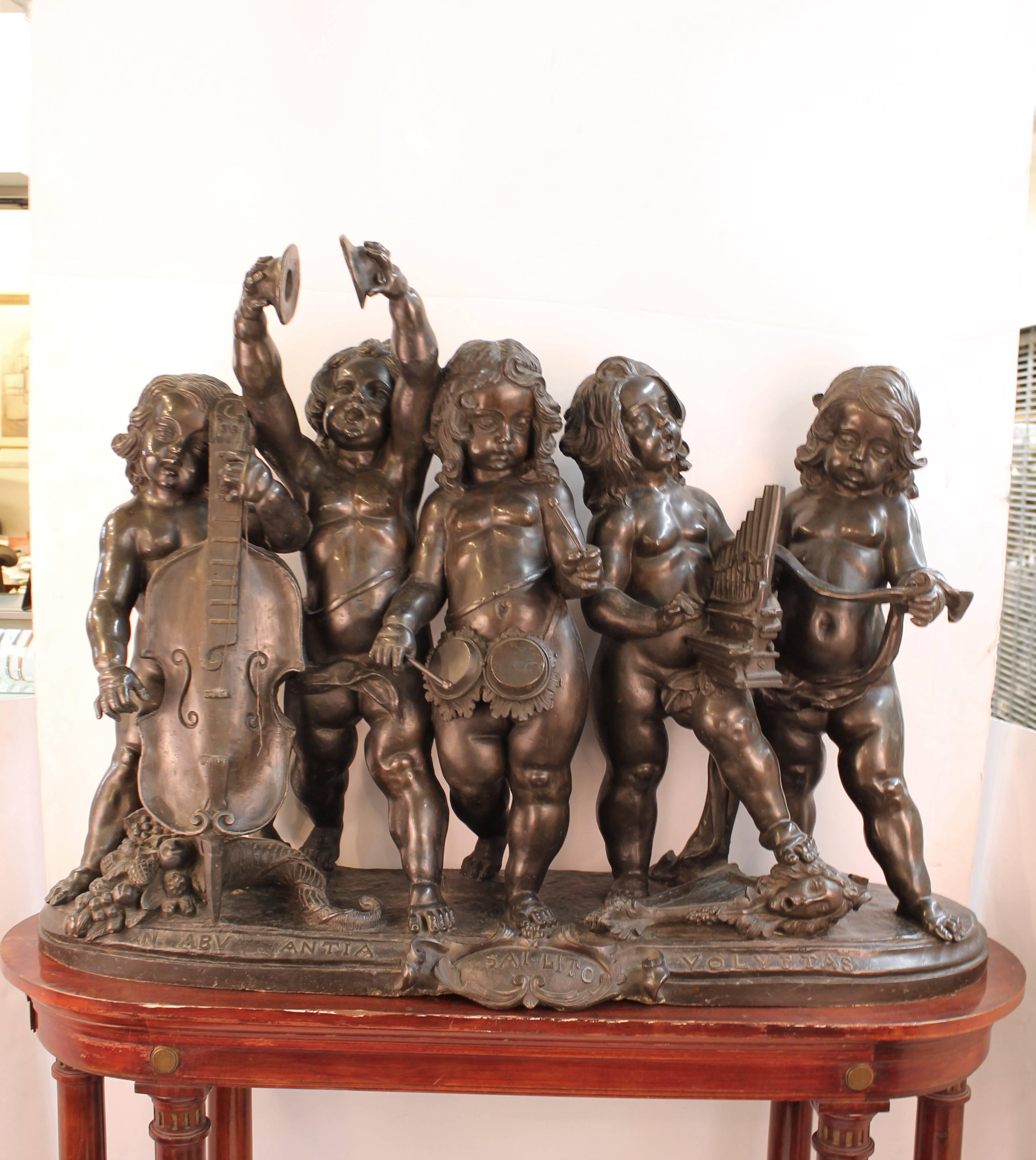 A Renaissance inspired bronze sculpture of five singing putti playing musical instruments atop an elaborately carved architectural wooden stand. The piece is attributed to Italian sculptor Ferdinando Vichi (1875-1945) and was produced in the early