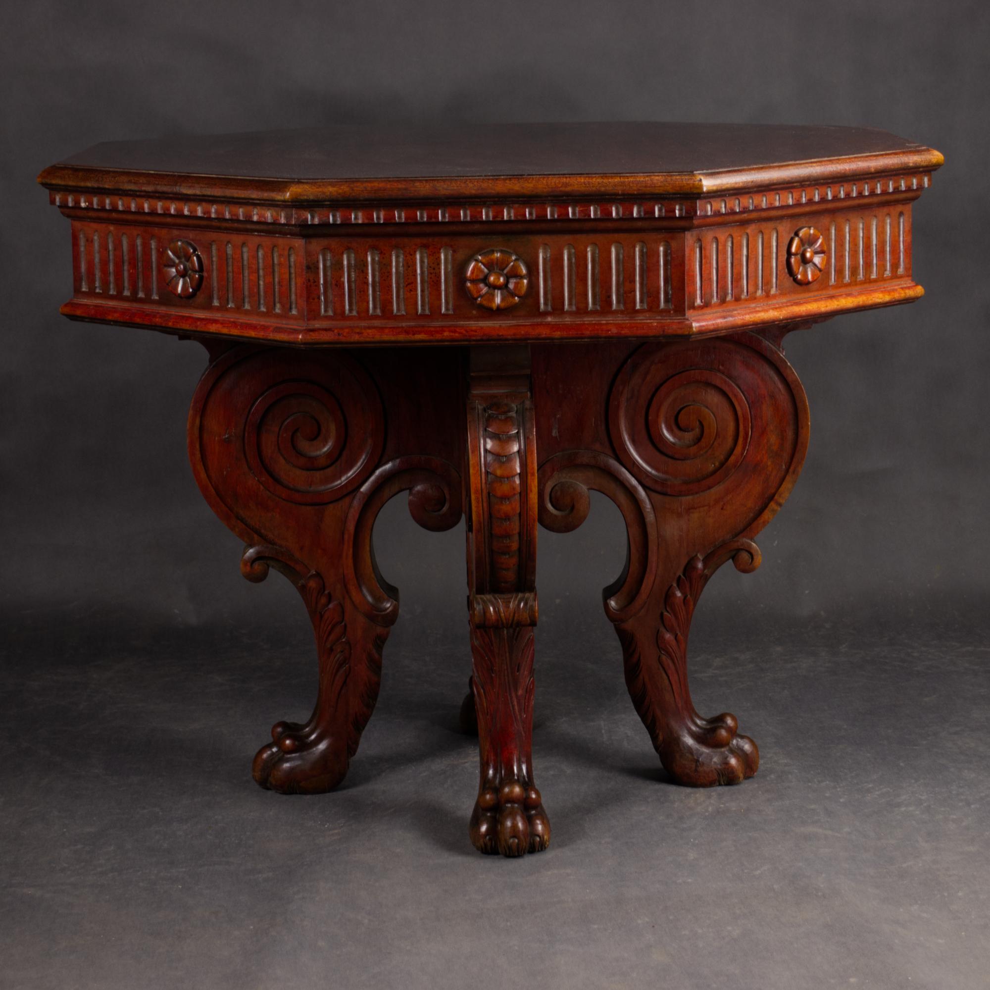 Elégante table centrale de style Renaissance italienne du XIXe siècle, fabriquée en noyer richement teinté. Le plateau octogonal est soutenu par une frise finement sculptée de rosettes florales et de détails cannelés, et comprend un tiroir latéral