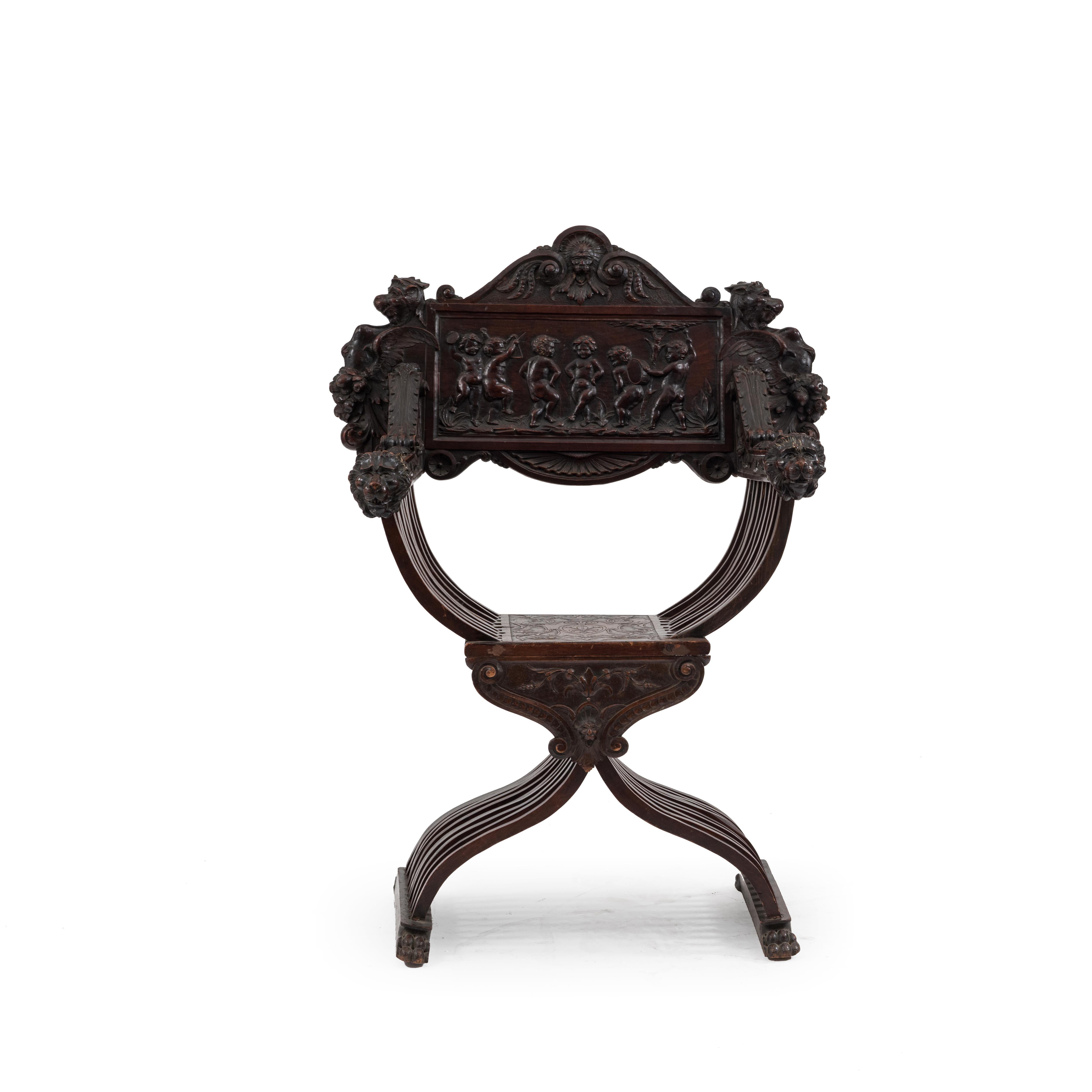 Italian Renaissance Savonarola style walnut armchair with cupids on back and lion carved arms (19th century).
  