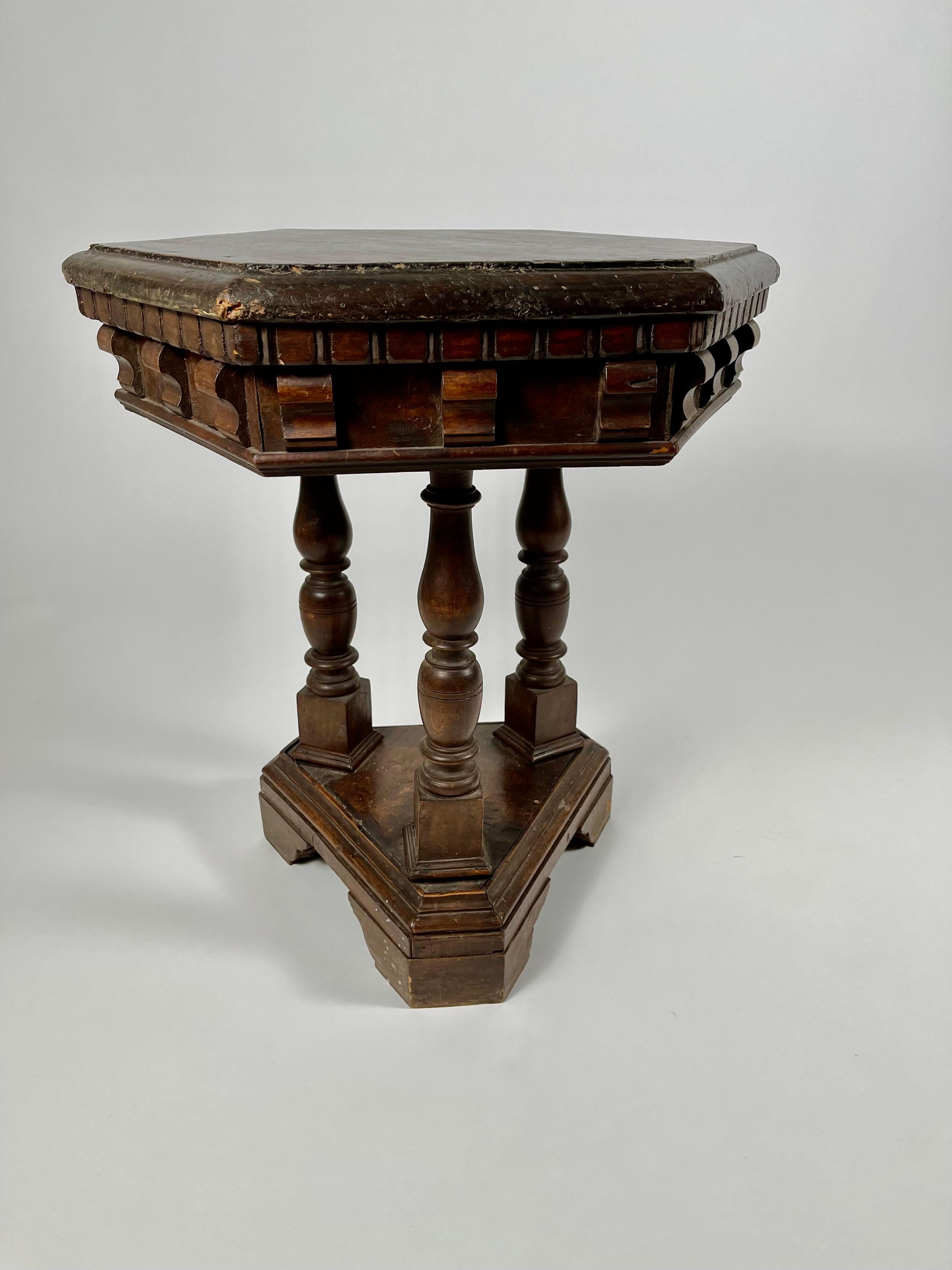 An Italian Renaissance Revival walnut side table with good patina and architectural form, the hexagonal top over a frieze with applied carved corbels, supported by three baluster turned legs raised on a triangular plinth base. Ideal for use as an