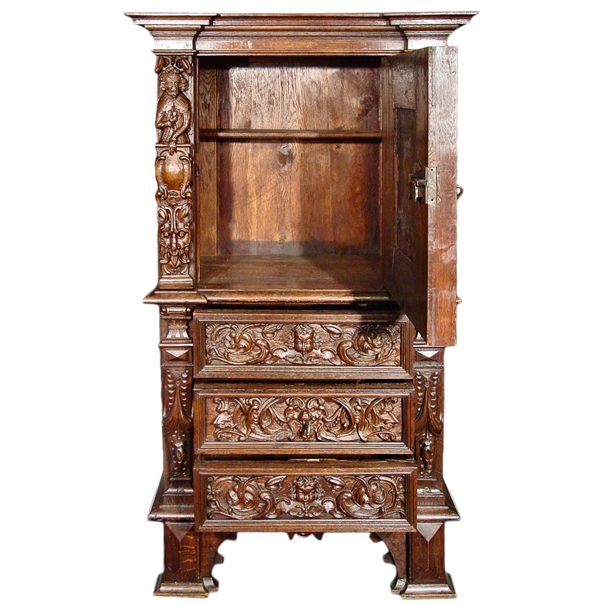 A heavily and richly carved Italian Renaissance st. mid 19th Century Oak side cabinet with one door and three drawers. The whole has exquisitely carved scrolled foliage design amidst angel faces and gargoyles. The door has a scene of Jesus, Mary and