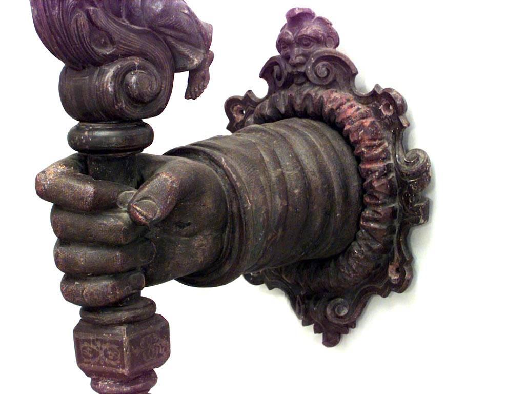Italian Renaissance-style (19th Century) carved and painted wall sconce shaped like an arm holding a torch with a kneeling figure.

