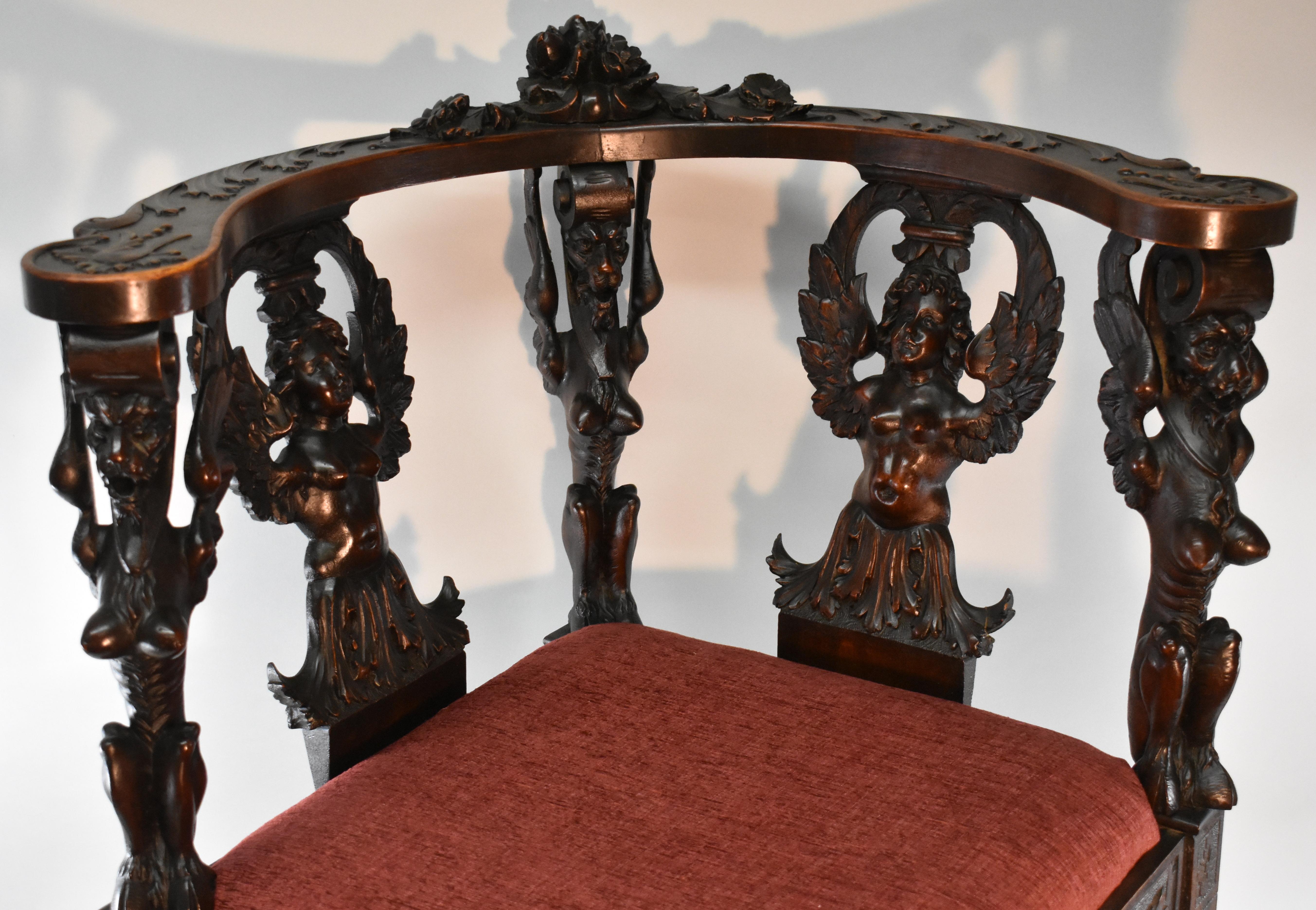 Italian Renaissance style carved mahogany corner chair. High reliefs of angels and griffins. Top of frame has leaf carvings and center floral group. Spindle legs are heavily carved. Original finish and condition with wonderful patina. Very nice