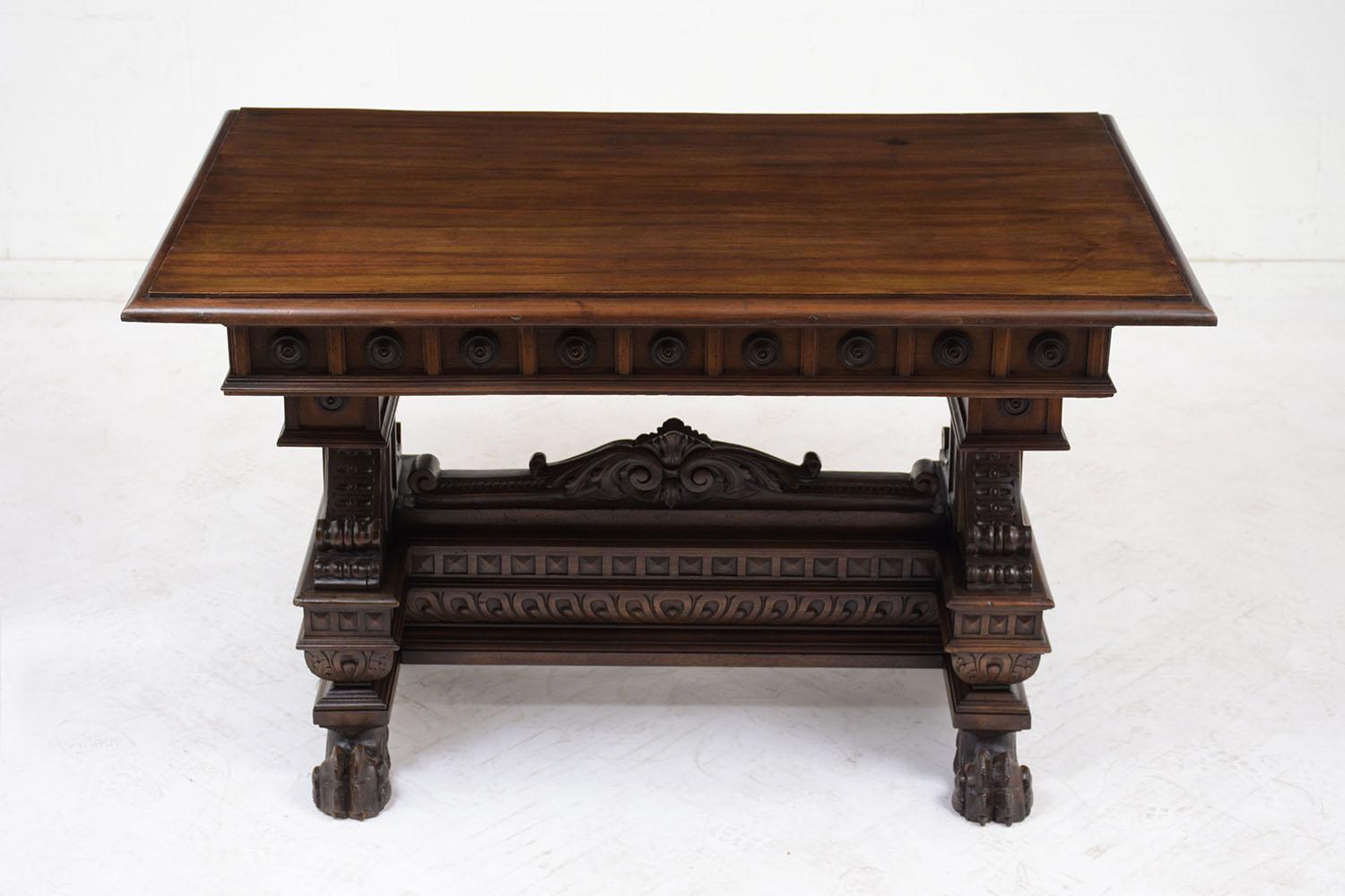 This Antique Italian Renaissance Style Library Table is made out of walnut wood stained in deep walnut color with a polished finish and has been fully restored. The writing table features handcrafted architectural designs accented by scrolls,