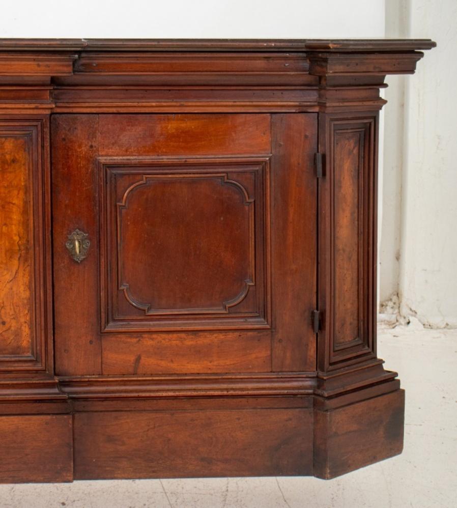 Italian Renaissance style walnut credenza, 19th century, with canted rectangular top above colonnettes separating four paneled doors opening to reveal movable shelves. In good antique condition with patina, wear consistent with age and