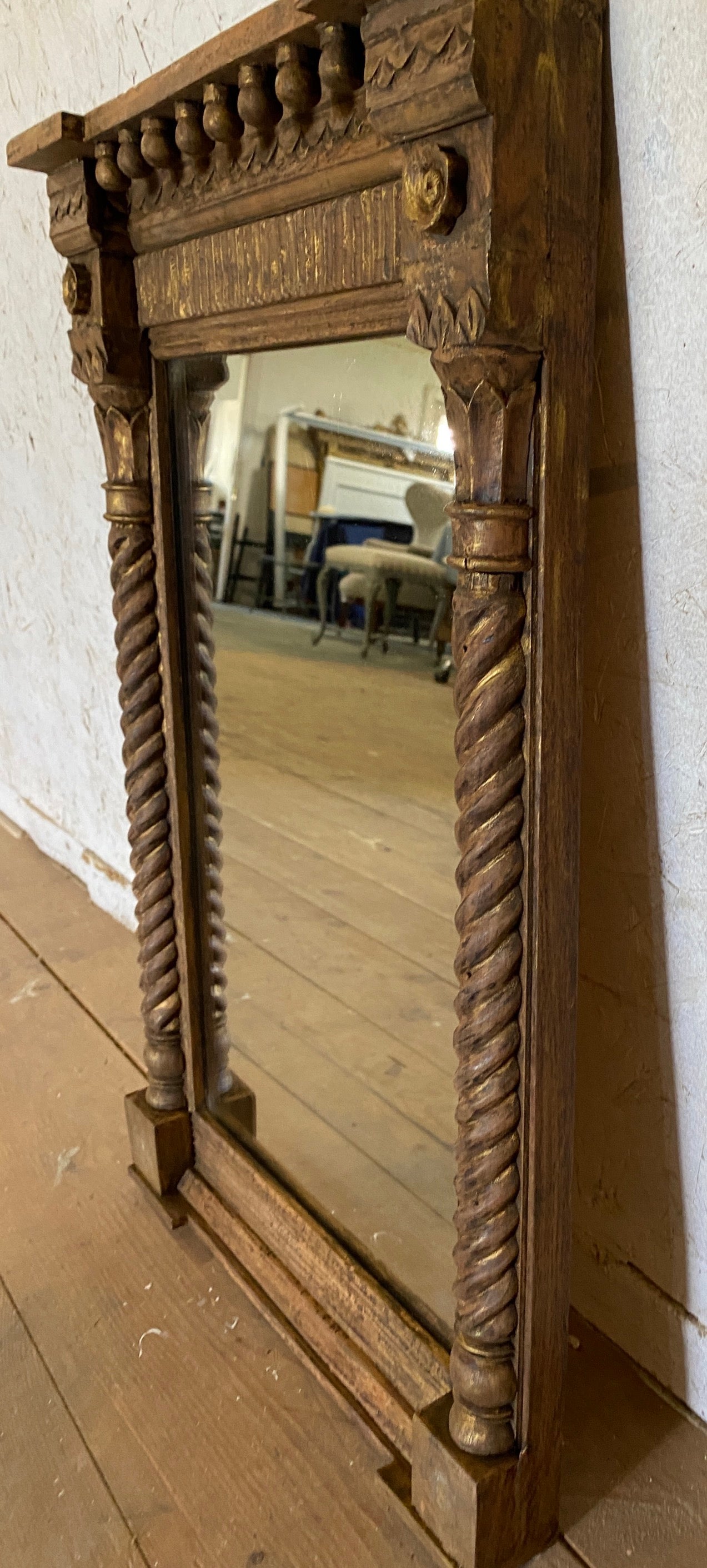 A smaller scale rectangular Italian gilt wood wall mirror in the style of a Renaissance tabernacle is pedimented with turned classical columns as supports. The original gilding, the old plate mirror, with some losses and the wonderful aged patina