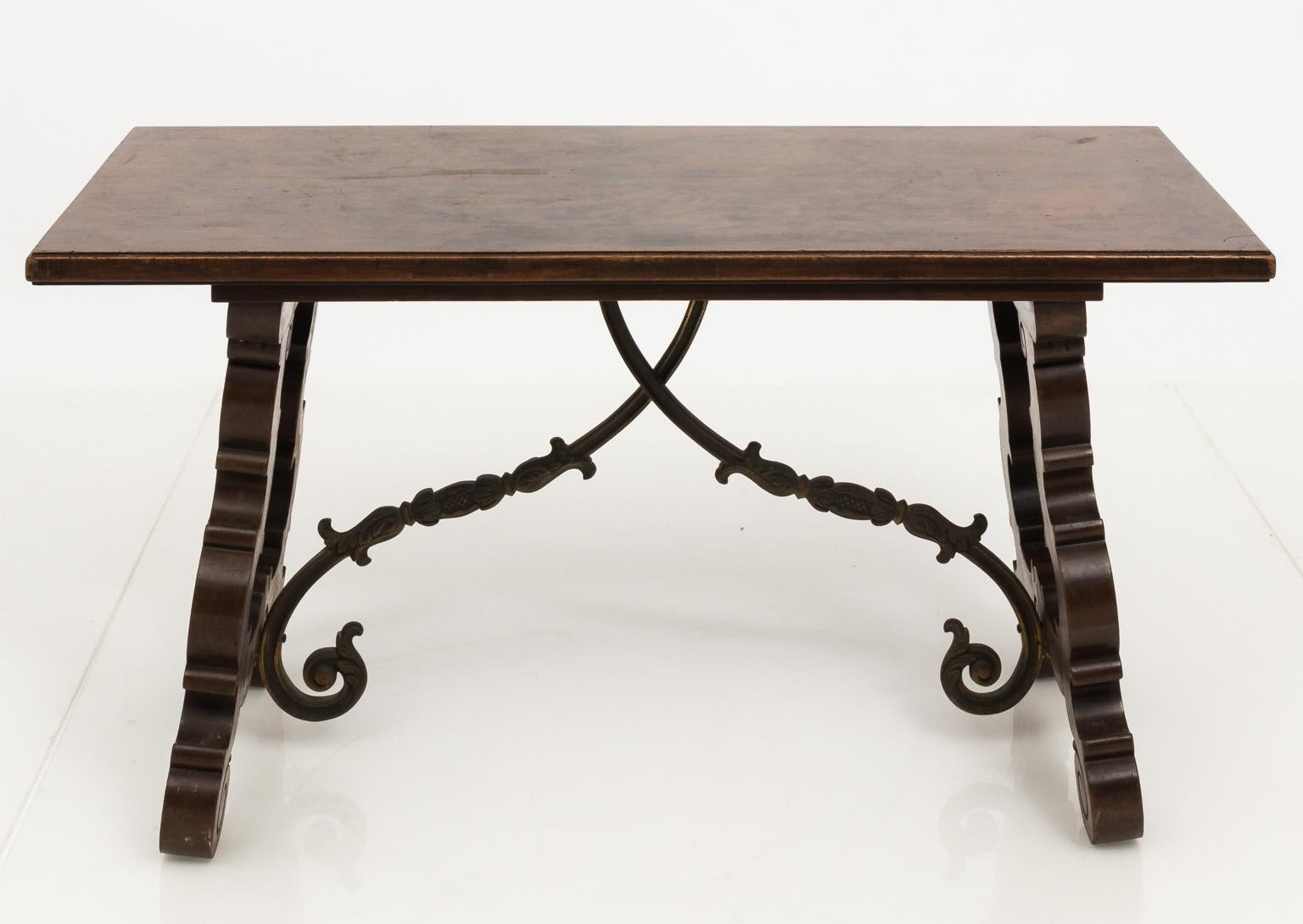 Italian Renaissance style walnut trestle coffee table with heavily carved scroll legs and a center scrolled cross stretcher in brass, circa 1950s.