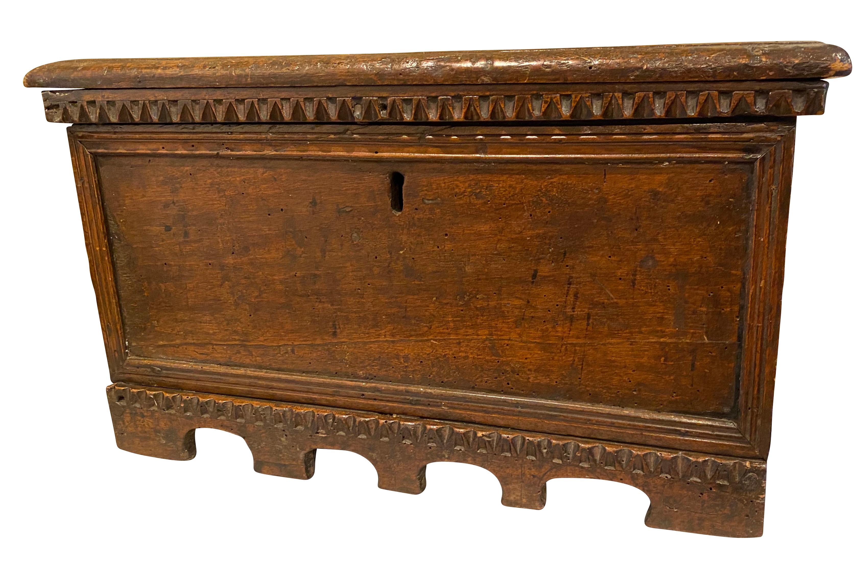A dwarf cassone with hinged top with chip carved edge over a paneled case with central keyhole, arcaded carved base.