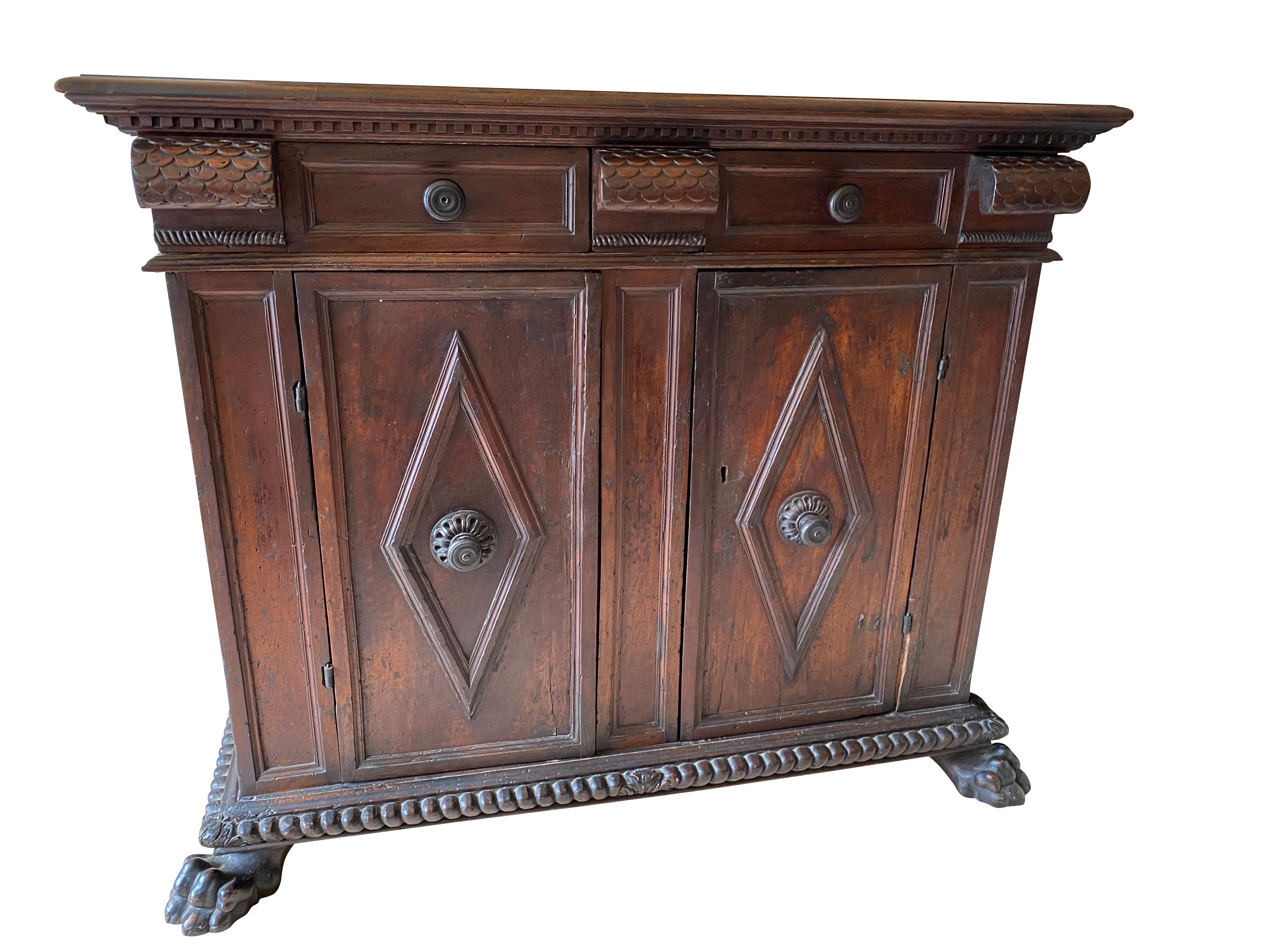 Rectangular molded top above two drawers with fish scale carved corbel form flanking drawers over a pair of paneled doors with diamond form applied molding, gadrooned carved base and lions paw feet.