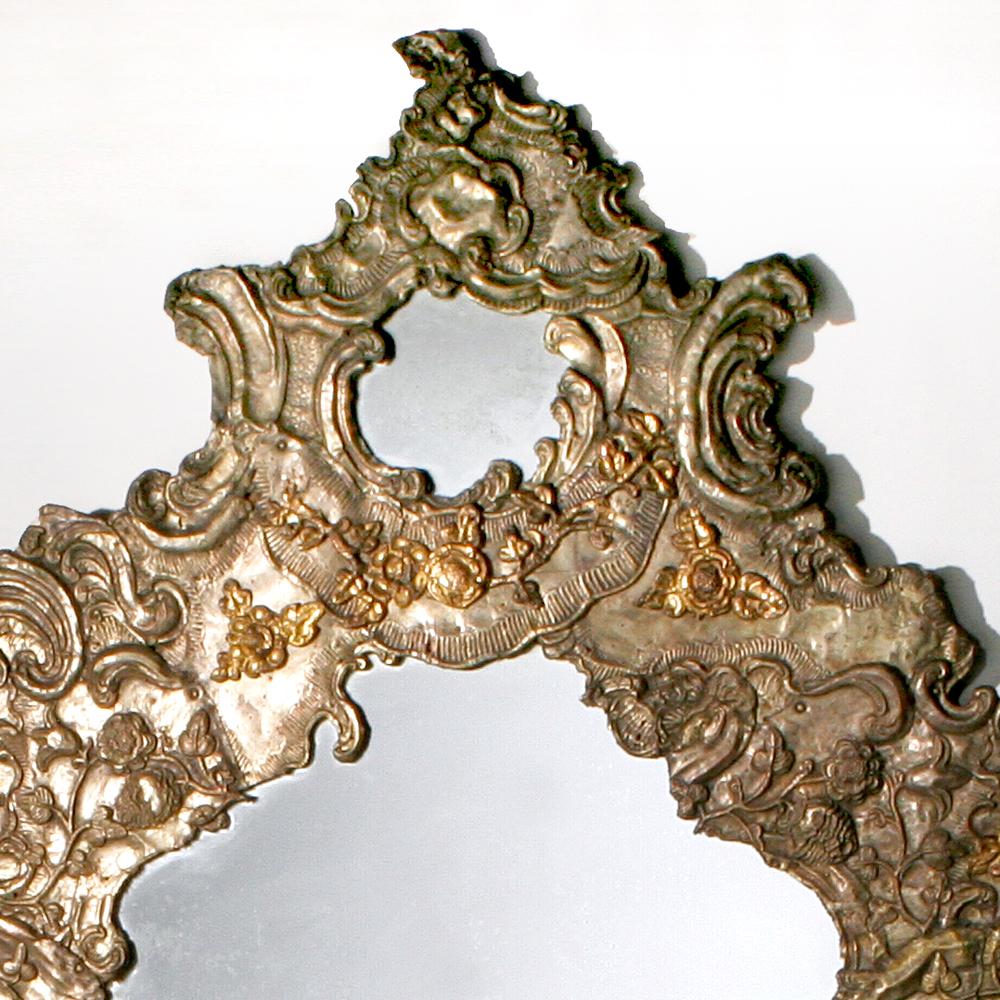 A rare find! An amazing 19th century Italian repousse mirror that is six feet high and four feet wide. Beautiful hammered metal ornamental design in a free form shape over a wood frame. The mirror appears sculpted with its raised decorative swirl