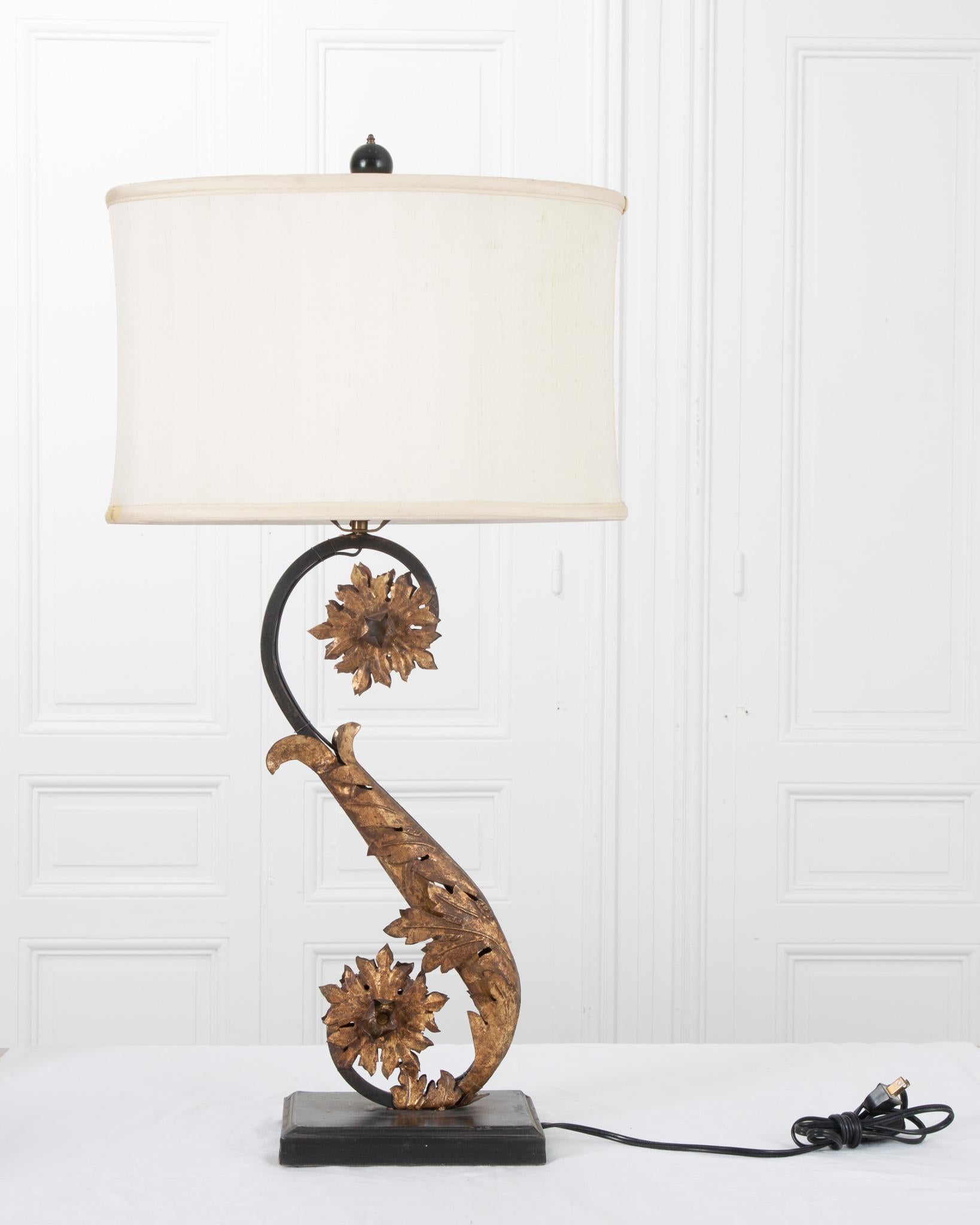 This elegant Italian reproduction lamp blends perfectly with modern or antique home decor! Fit with a custom oval shaped silk shade. The lamp features detailed gilt leaves and flowers wrapped around the scrolling ‘S’ shaped metal body. The metal