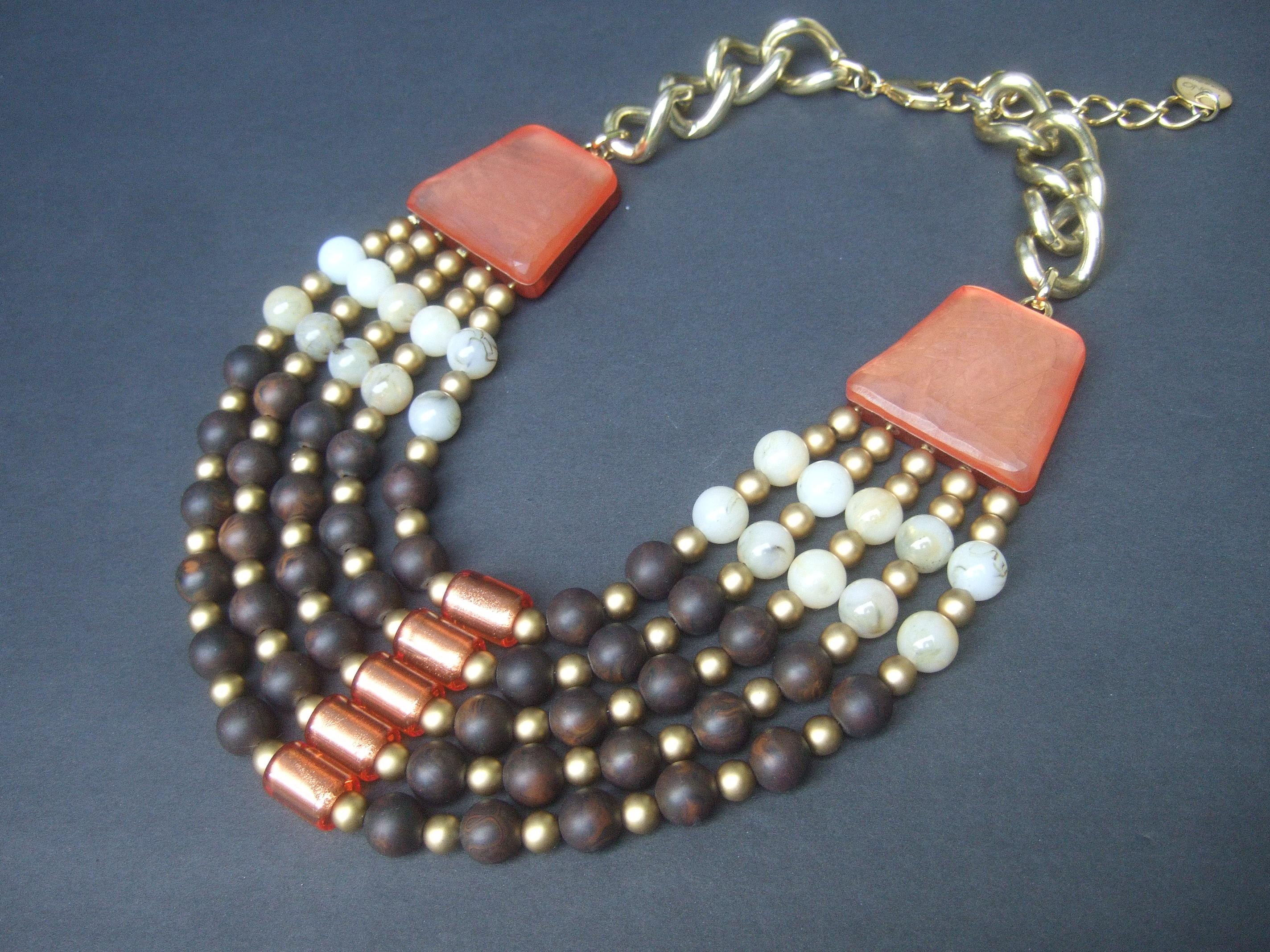 Italian resin beaded bib statement necklace designed by Pono  circa 1980s

The unique large scale bib necklace is comprised of five strands of resin beads in various sizes & colors that range from dark brown, matte gold, milky beige & copper peach