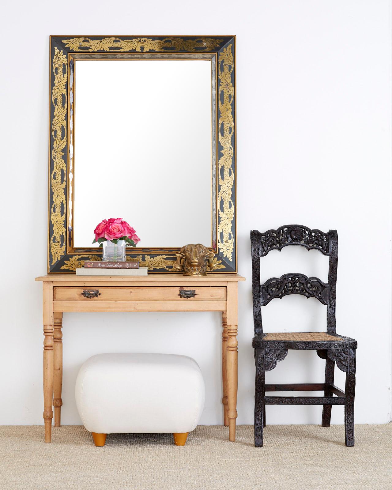 20th century Italian mirror with a thick reverse gold-leaf painted eglomise style glass border. Features a neoclassical scrolling acanthus gilt design on all four sides with a dramatic black ground. Fastened with small decorative pins having glass