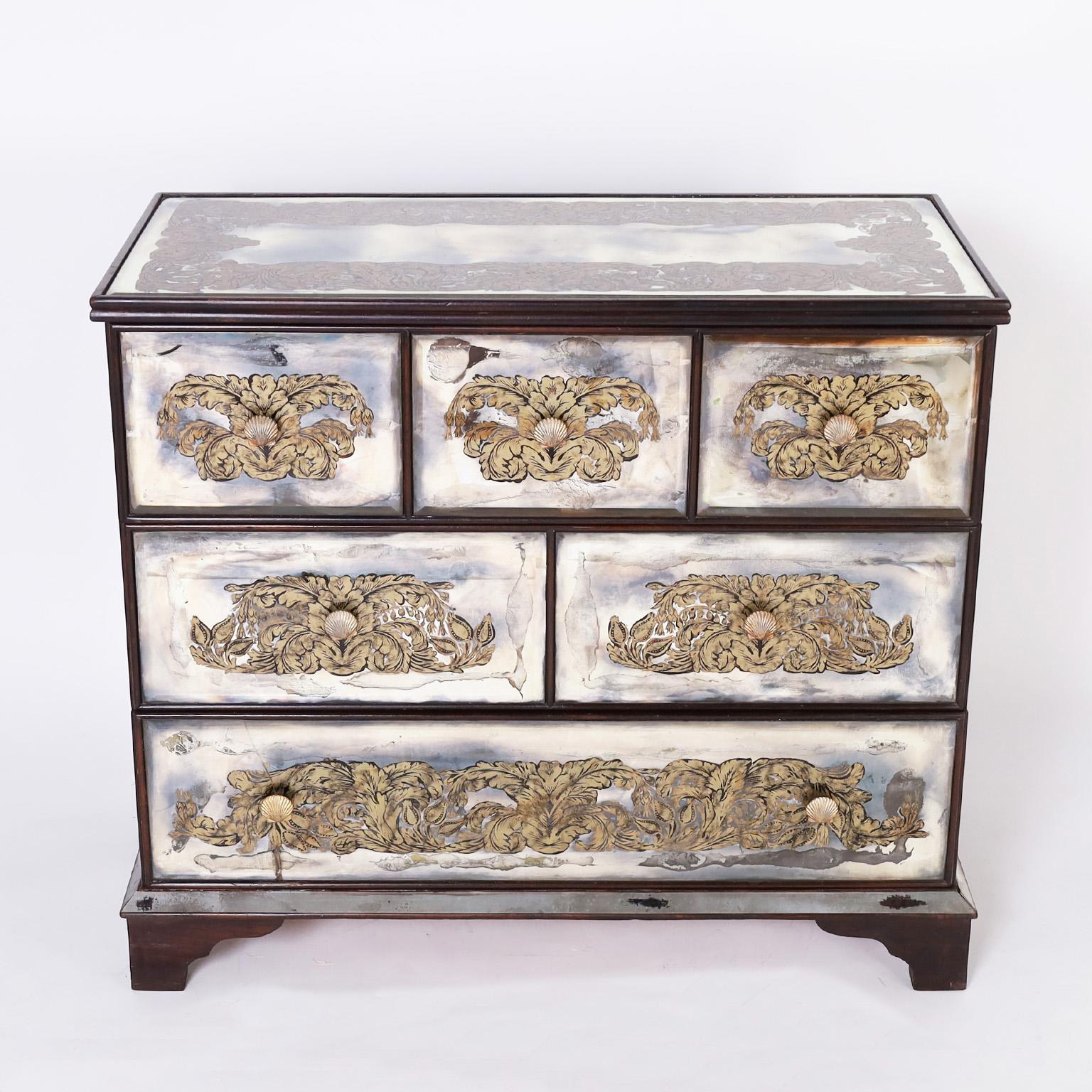 Hollywood regency style Italian chest with six drawers having an ebonized frame and featuring beveled mirrors on the top, front, and sides decorated with dramatic églomisé floral designs and brass seashell hardware. Bottom drawer with a small crack.