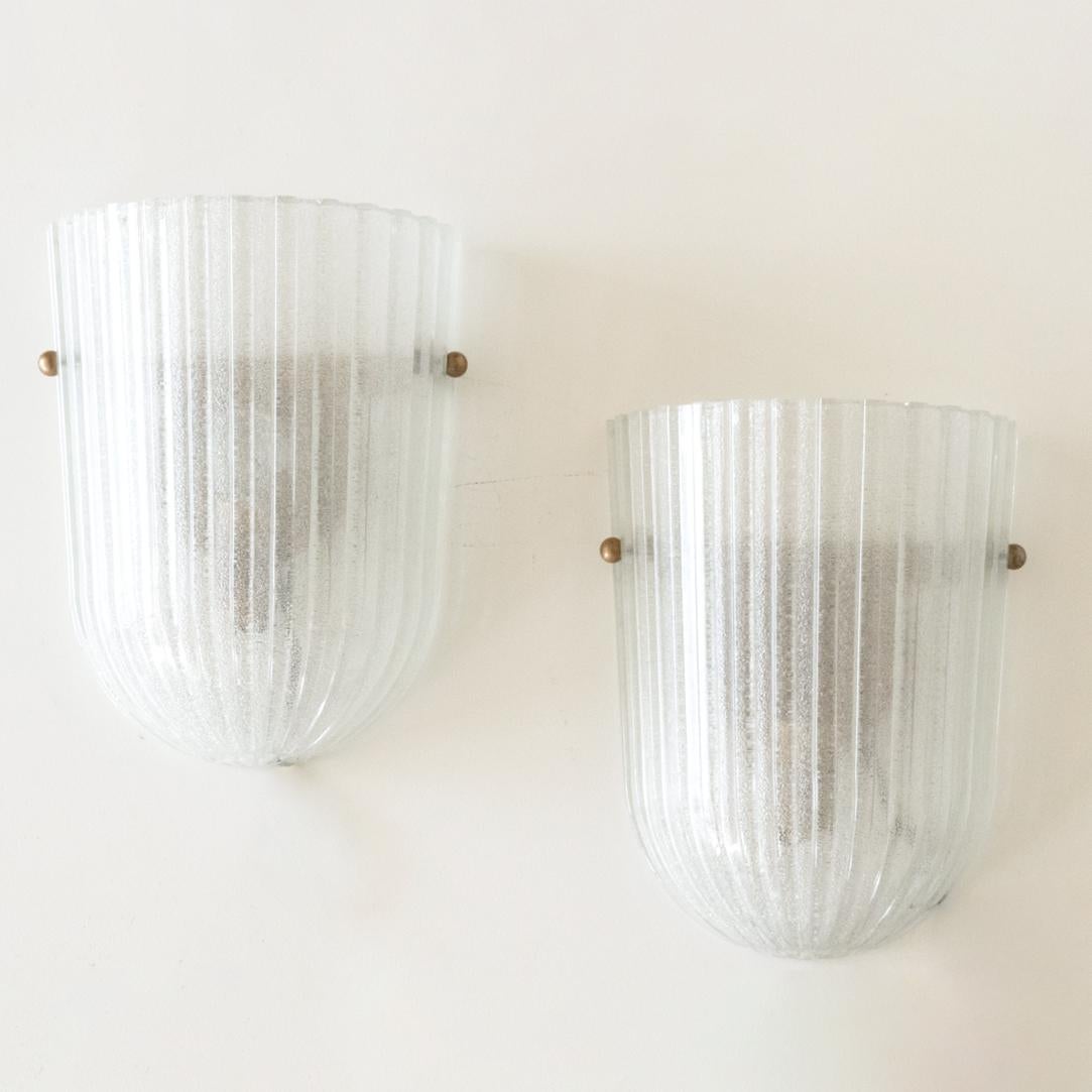 Beautiful pair of Italian ribbed glass sconces with brass ball detailing. Oblong frosted glass with wide ribbed detail on glass. New brass interior fitting and socket. 

 