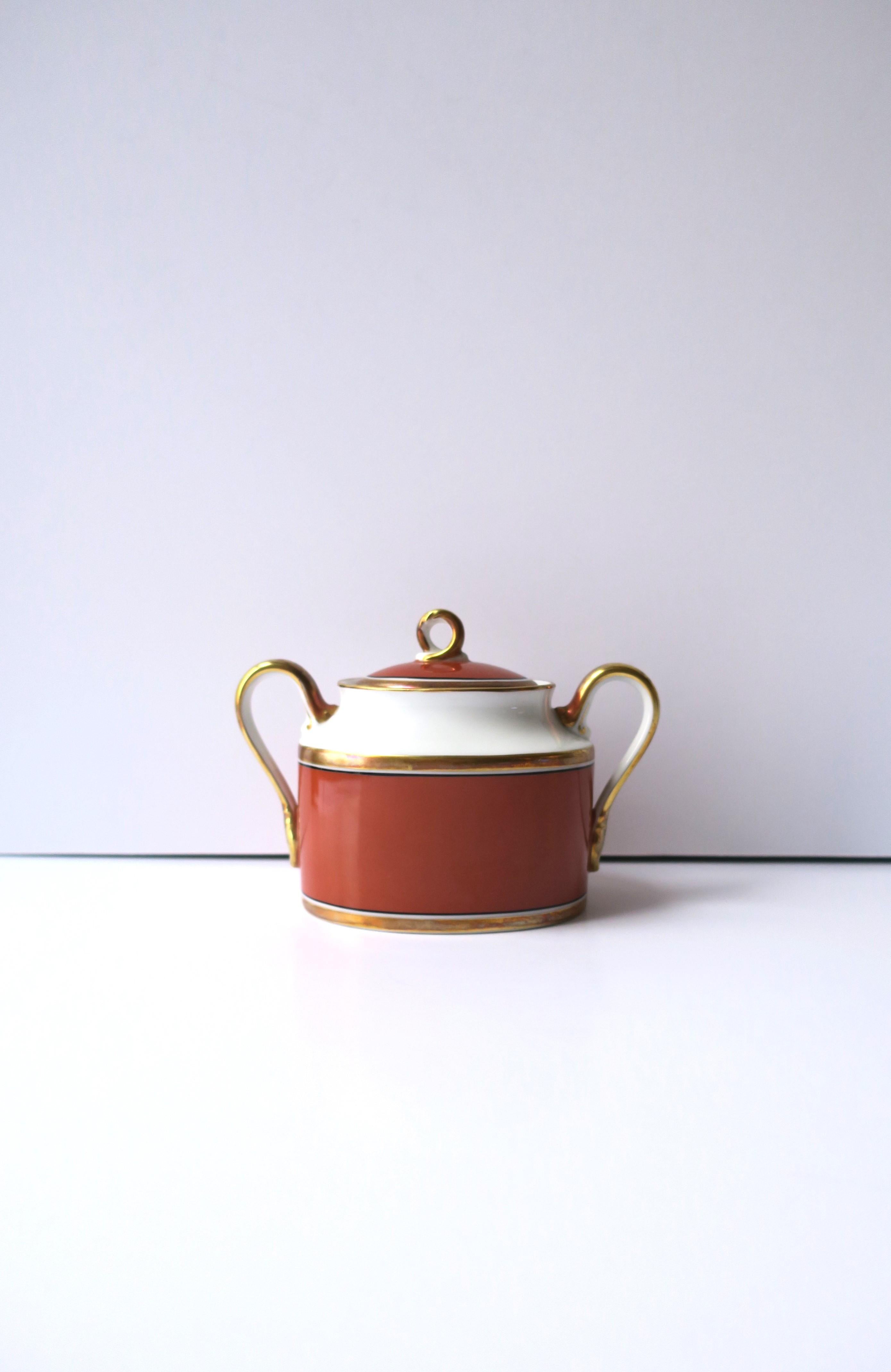 A vintage Italian Richard Ginori 'Contessa' gold and terracotta rust-red porcelain sugar bowl and lid, circa late-20th century, Italy. Piece is hand decorated with gold band detail around lid rim, center and base, and on handles. This 'Contessa'