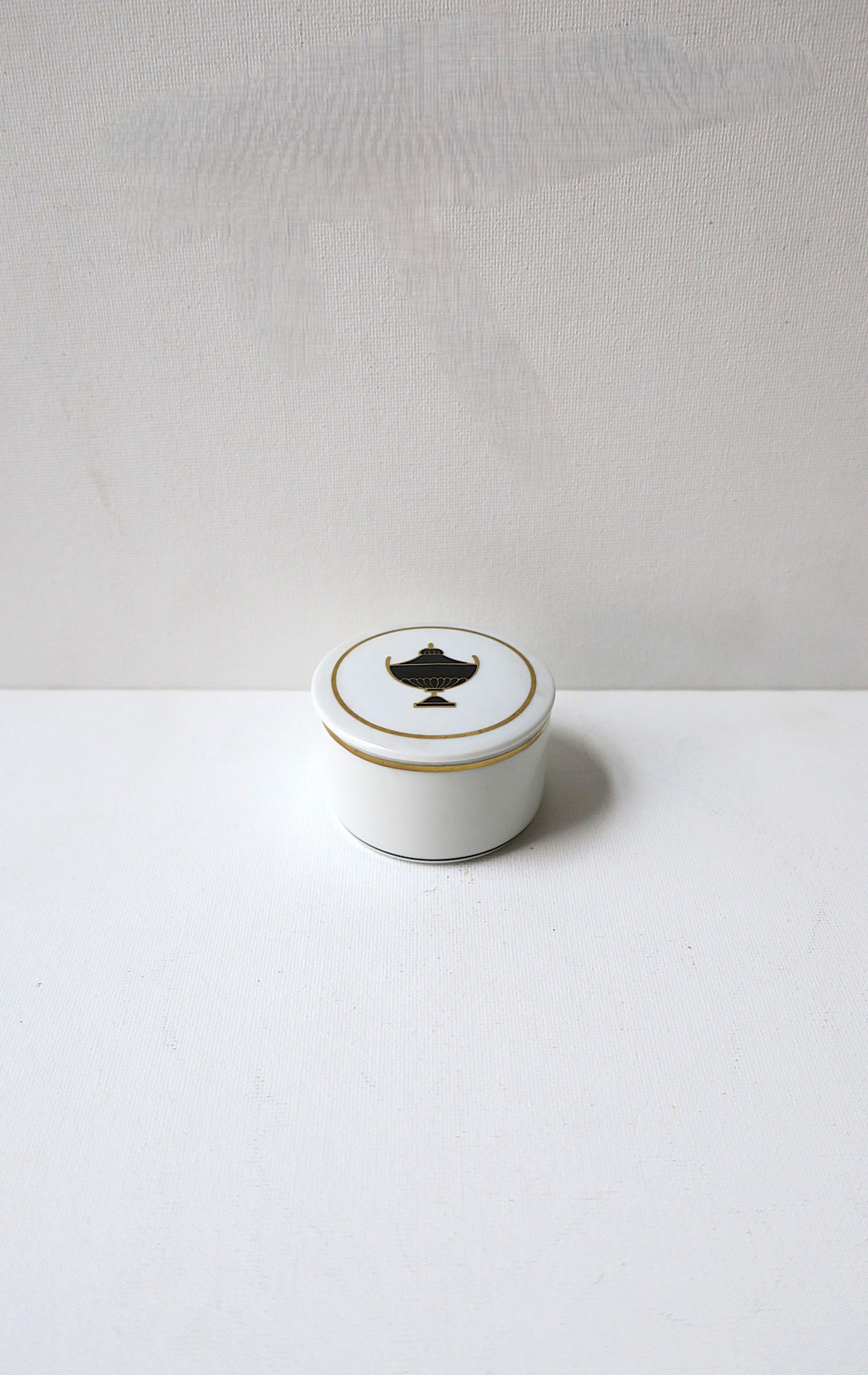 Pequeño joyero de porcelana italiana, de estilo neoclásico, obra del diseñador italiano Richard Ginori, entre mediados y finales del siglo XX, Italia. Caja de porcelana redonda con diseño de urna negro y dorado en la tapa, acabada con detalles