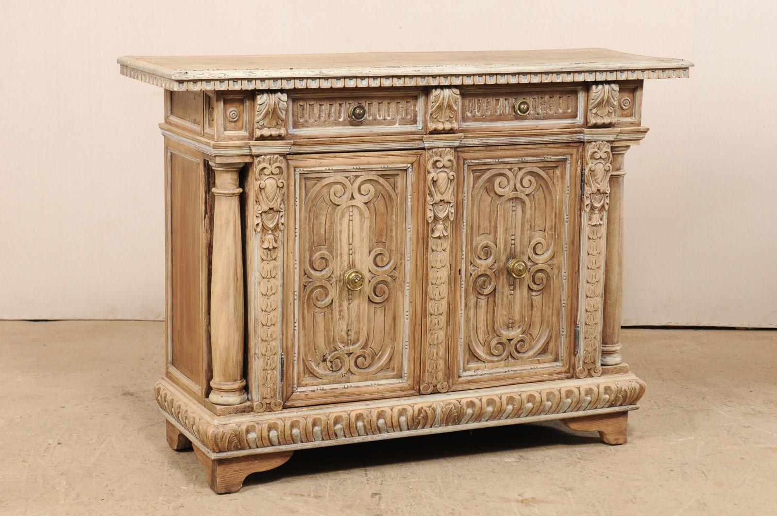 An Italian credenza console with intricate carved details from the 19th century. This antique buffet cabinet from Italy is elaborately carved with various egg-and-dart, foliage, and scrolling motifs. The rectangular-shaped top overhangs the