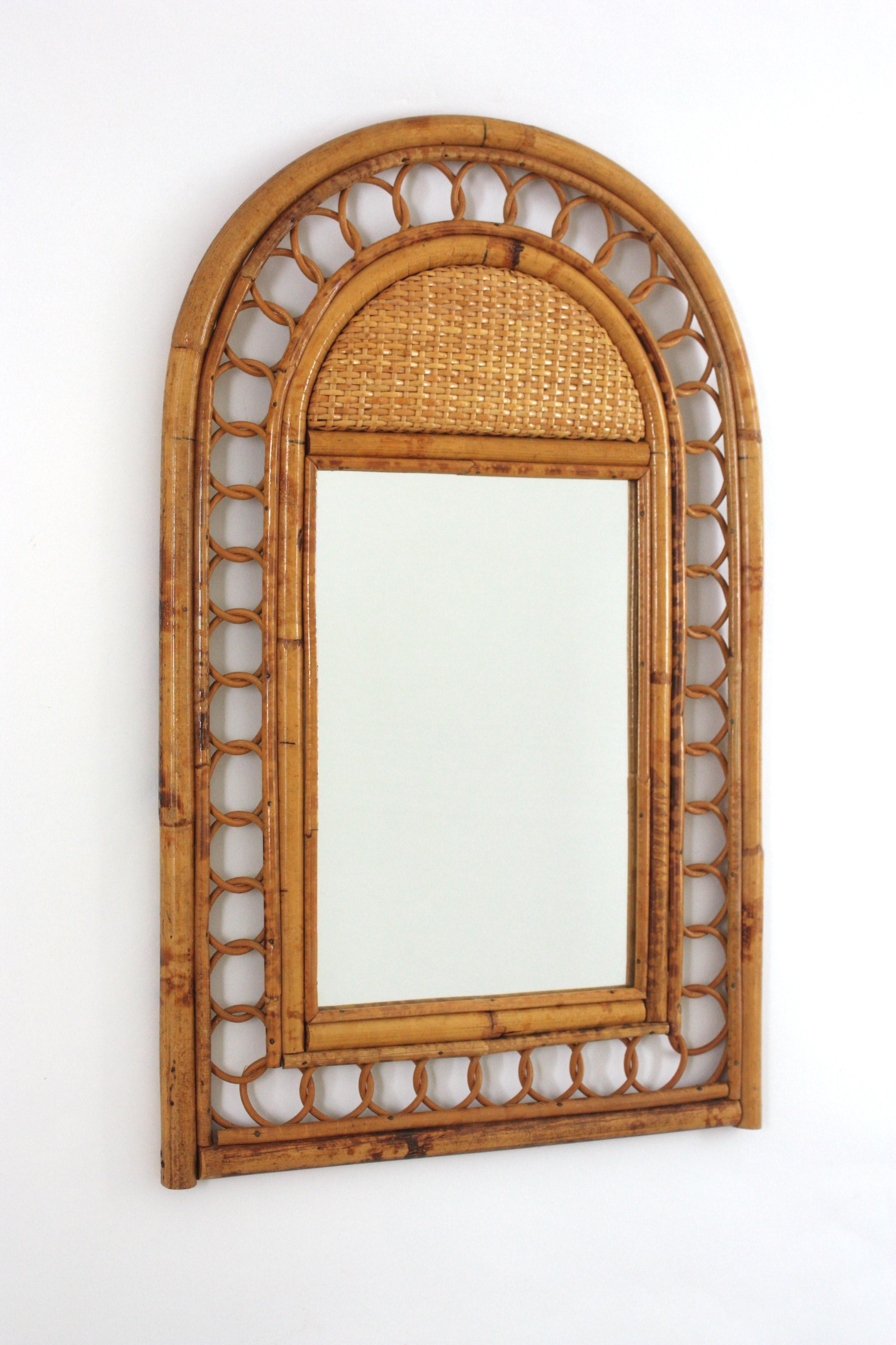 Eye-catching Mid-Century Modern Franco Albini style handcrafted bamboo and rattan mirror with arched top and woven details. 
This coastal mirror features a double bamboo frame with rattan circles decorations between the bamboo/rattan canes. A
