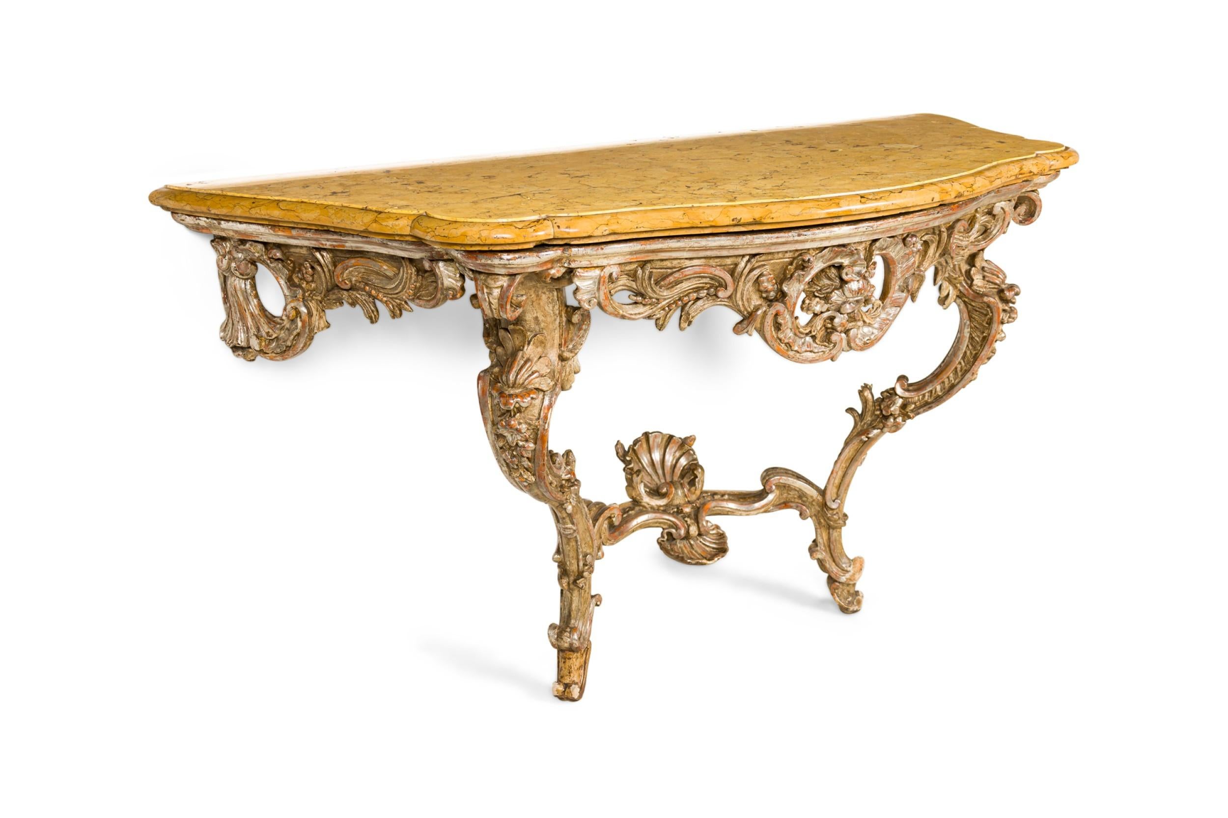 Console rococo italienne (18ème siècle) à console en argent doré, avec des pieds en forme de volutes sculptées, reliés par une entretoise et un tablier sculpté en filigrane, supportant un plateau en marbre jaune de Sienne.