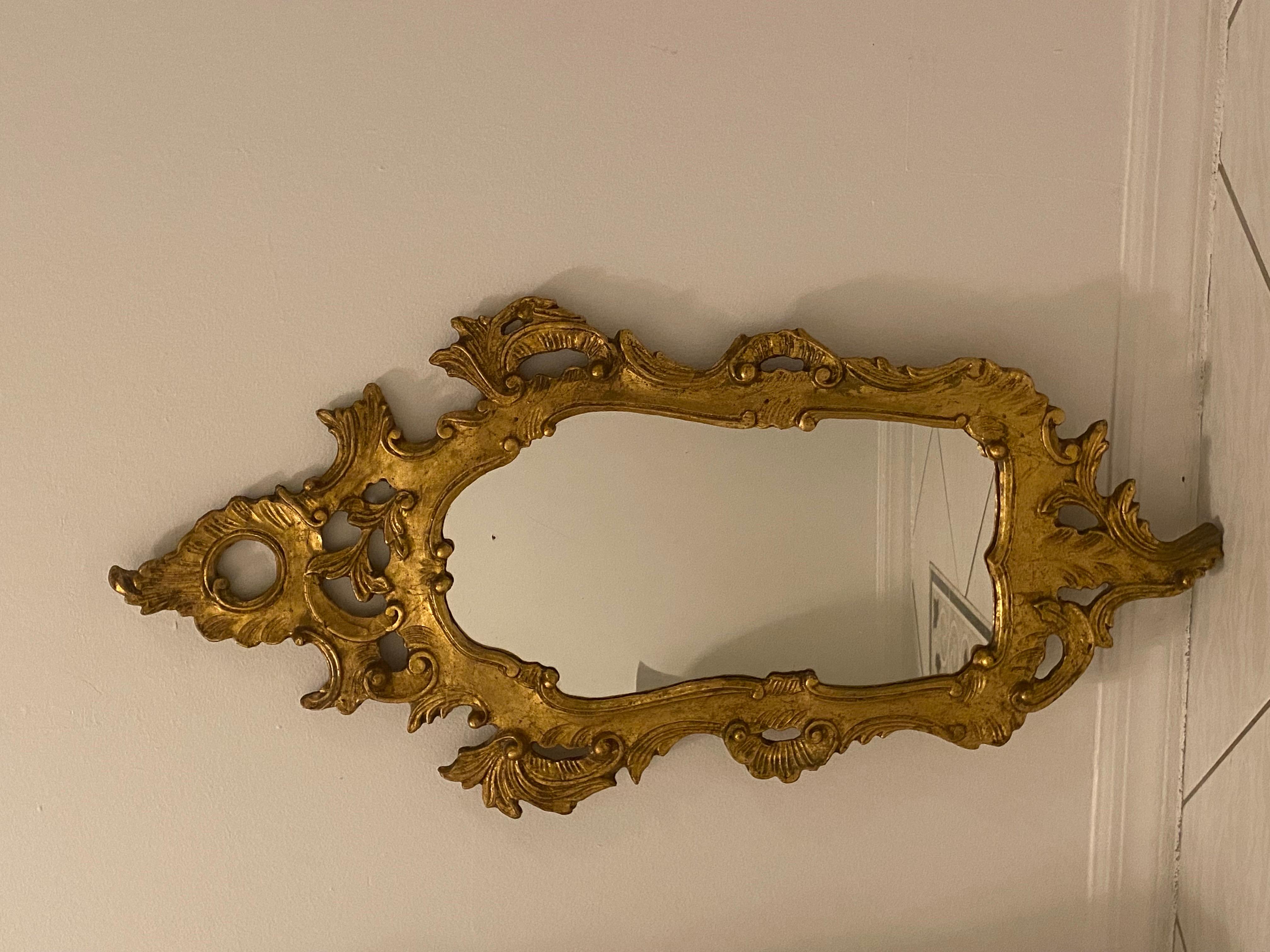 Der prächtige antike Spiegel im Stil des Rokoko ist aus geschnitztem Goldholz mit kunstvollen astförmigen Schnitzereien in C-Form und kreisförmigen Motiven und Schriftrollen gefertigt. 

Das Stück ist in tollem Vintage-Zustand.

Italien, 1950er
