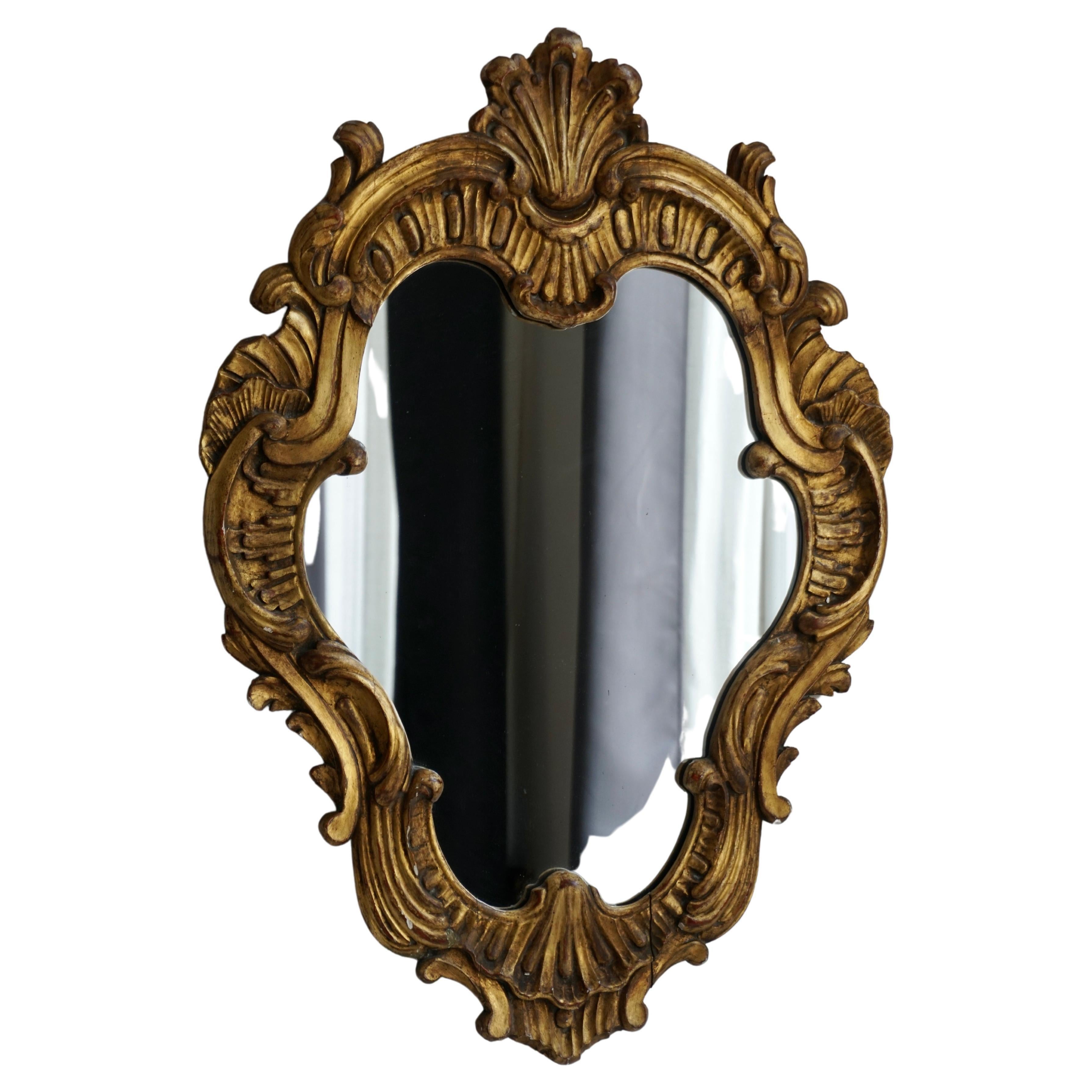 A gorgeous antique mid 20th century Italian Rococo style gilded wood mirror. This stunning mirror retains the original old mirror glass with an ornate scrolling leaf design and a lovely gilt patina.  

Dimensions; 21