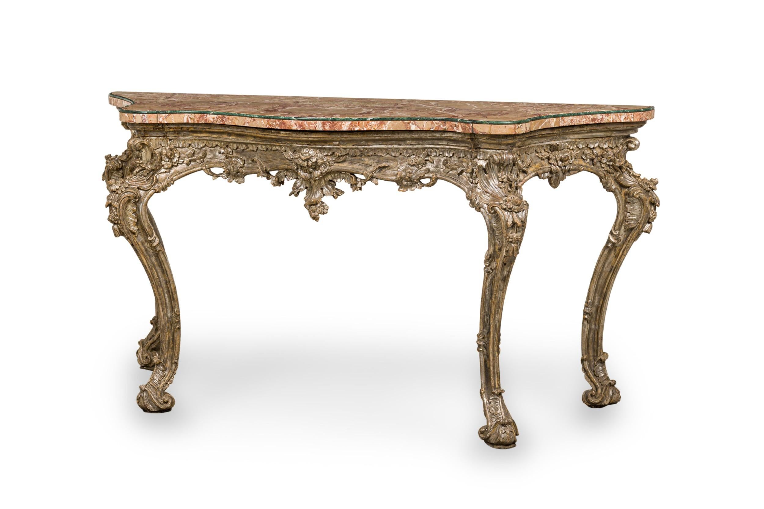 Italian Rococo console table with an ornately carved foliate design silver gilt frame supporting a shaped blush marble top with rounded green marble trim.
 

 Minor losses to finish and decorations on base.
