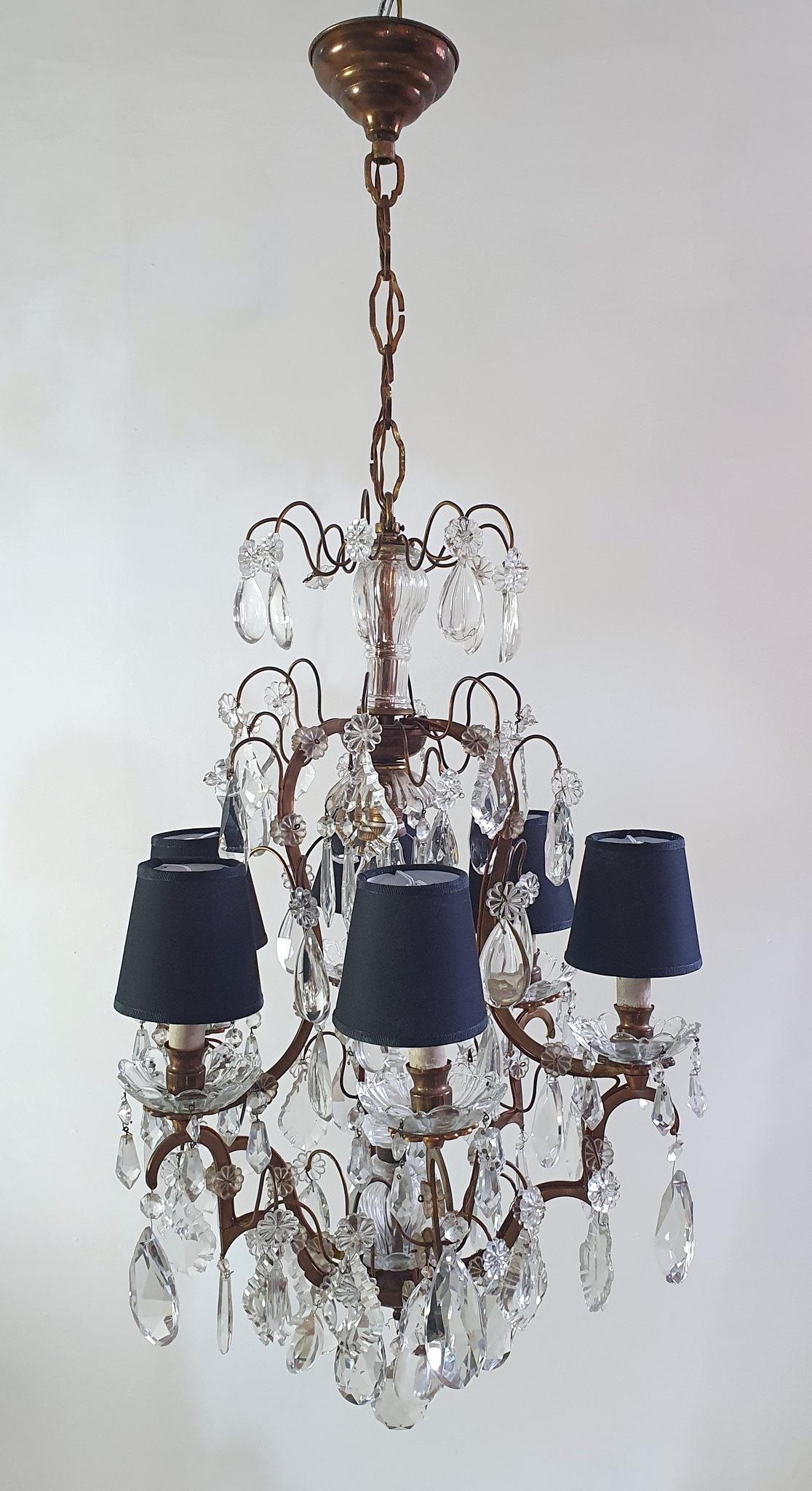 This is a classic Rococo style chandelier hand made in Italy circa 1940 with an array of crystals on a brass frame. The chandelier has six candle shaped E14 lights which have been paired with black lampshades which really is a great combination of