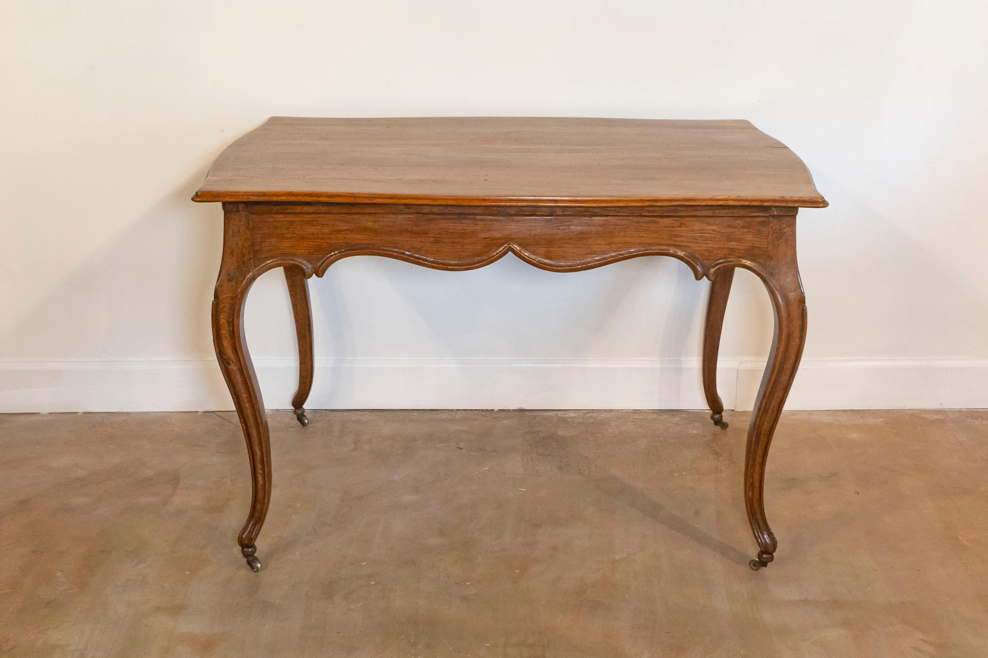 Tavolo in stile rococò italiano in noce e oak degli inizi del XIX secolo, con piano a serpentina, grembiule intagliato, gambe a cabriola e piccole rotelle. Creato in Italia durante i primi anni del XIX secolo, questo tavolo in stile rococò presenta